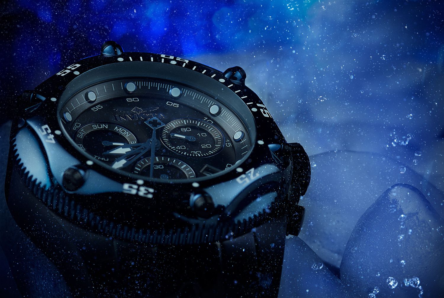A black diving watch with chronograph features photographed underwater against a dark blue starry background.