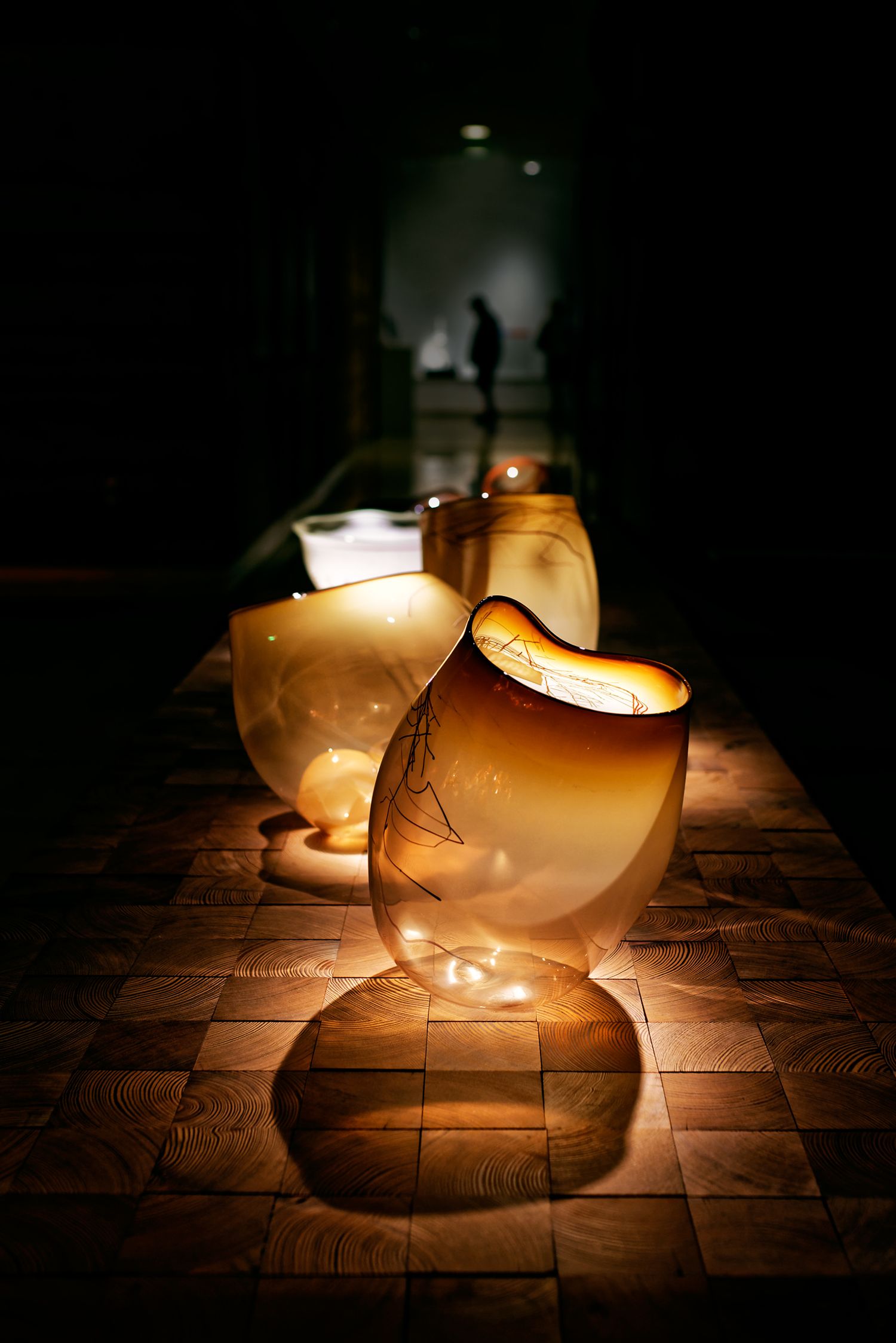 Glowing frosted glass lanterns illuminate a dark brick pathway creating an atmospheric mood at night.