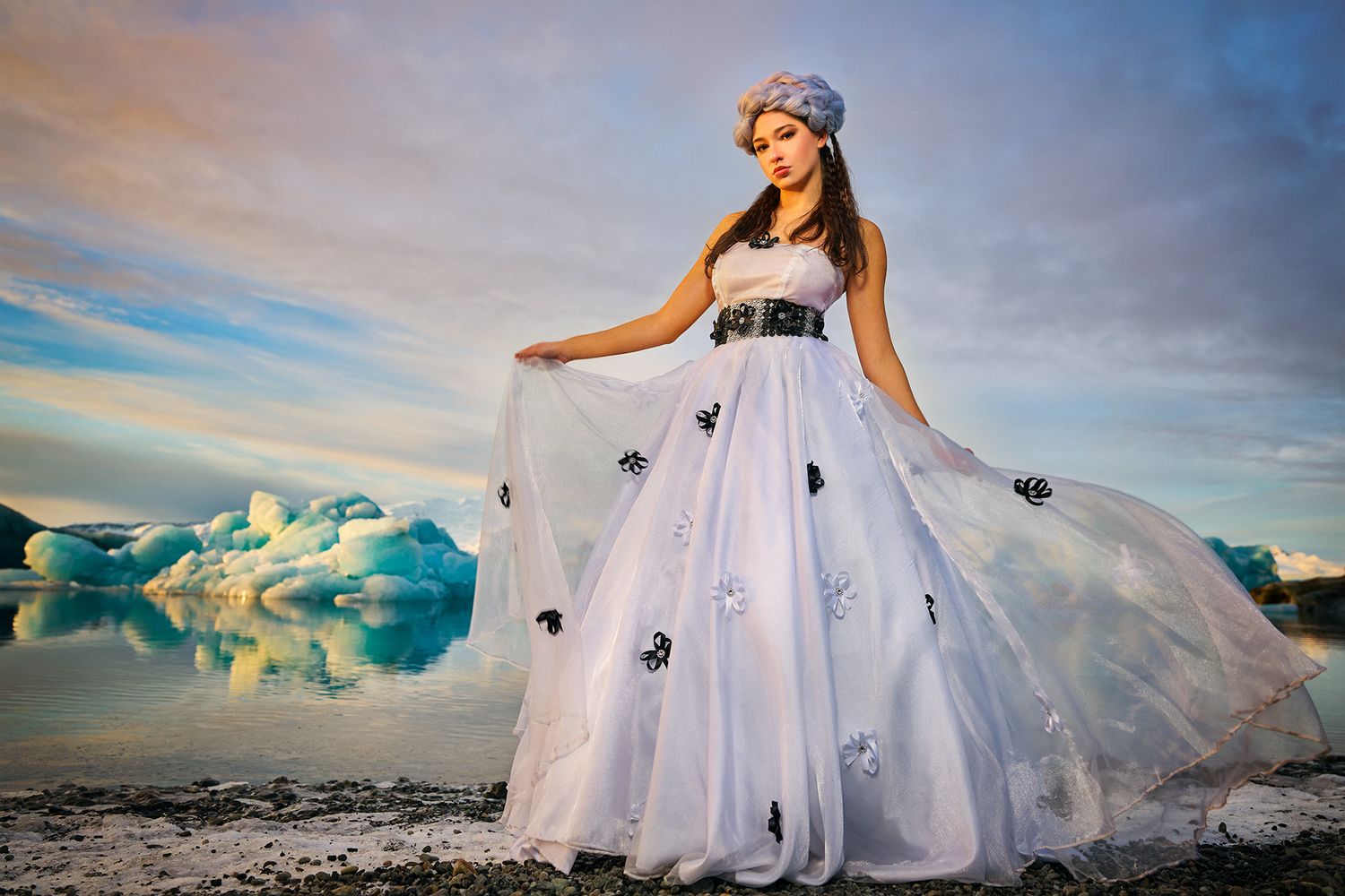 A dramatic wedding dress photoshoot against a backdrop of blue glaciers and sunset sky in Iceland.