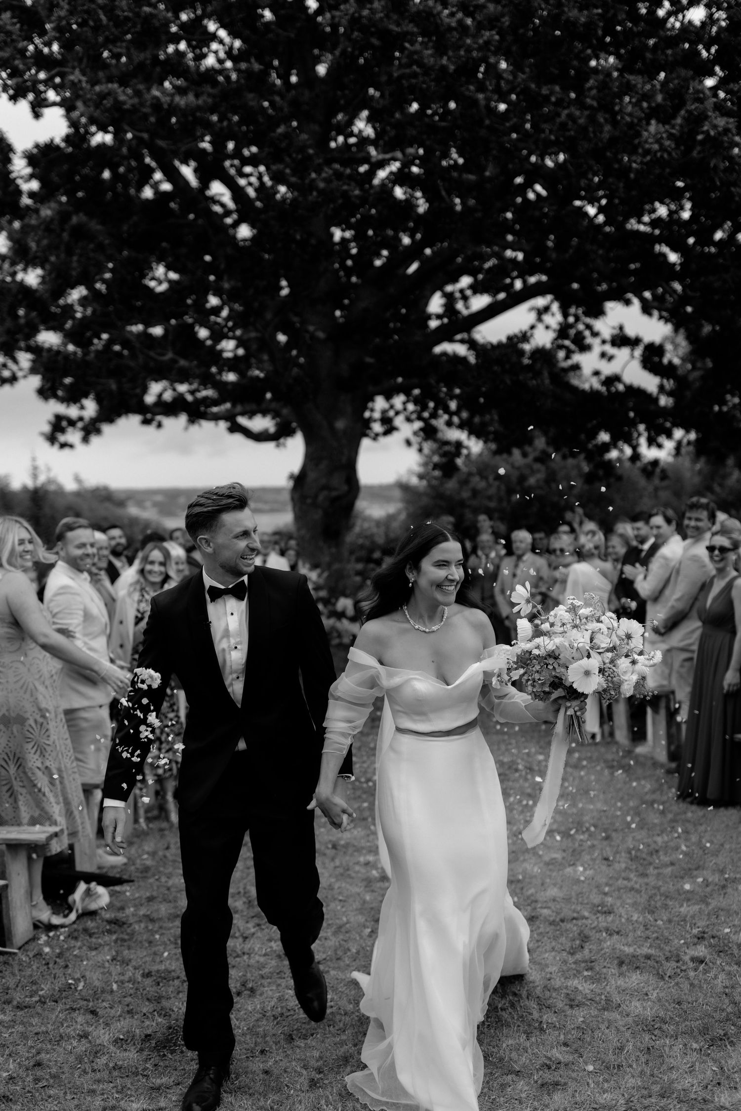 Black and white photos show a wedding celebration outdoors under trees with guests gathered on grassy lawn.