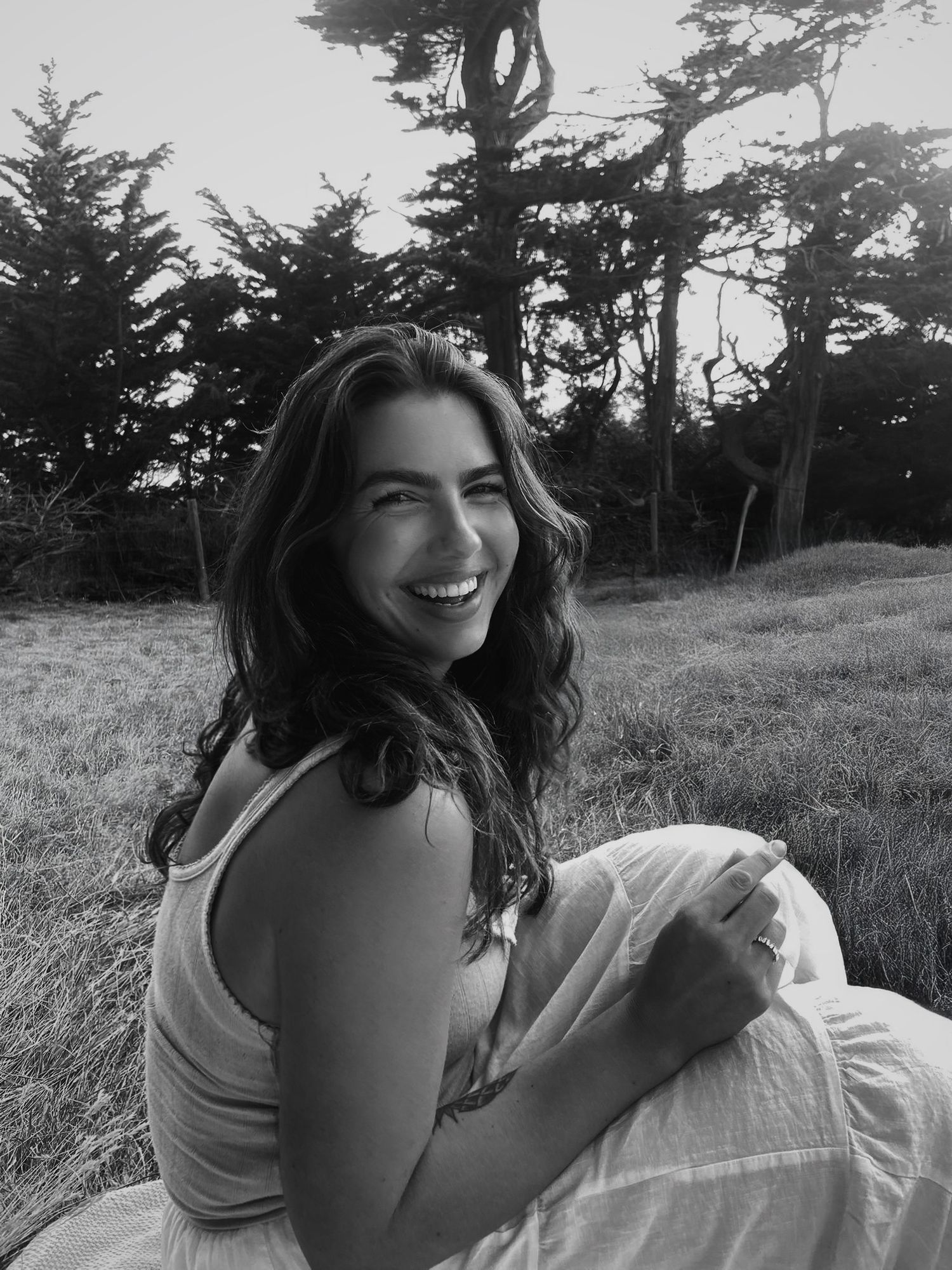 Person lounging in natural setting with trees in black and white photograph.