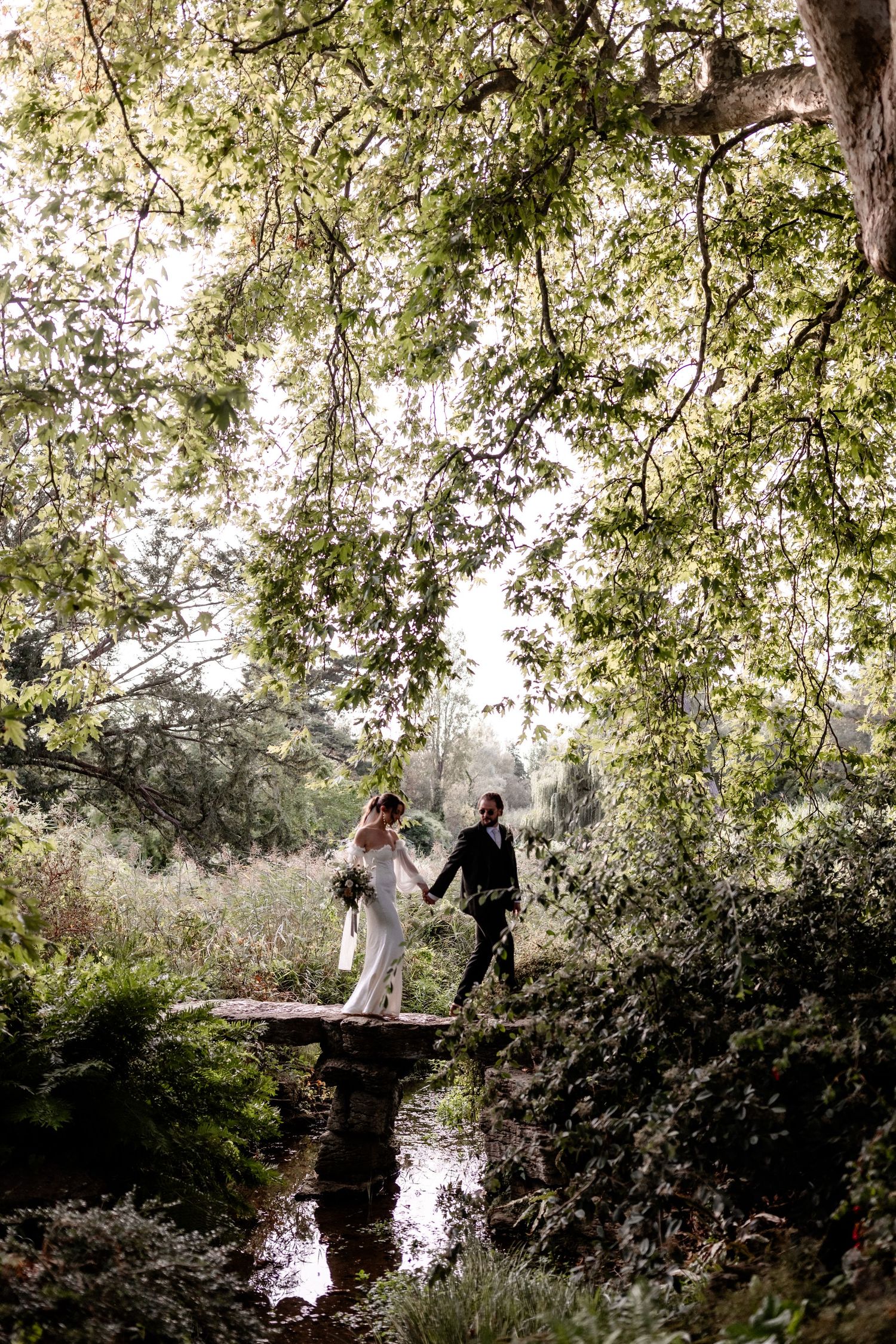 Wedding couple sharing romantic moments under blooming trees near a pond.