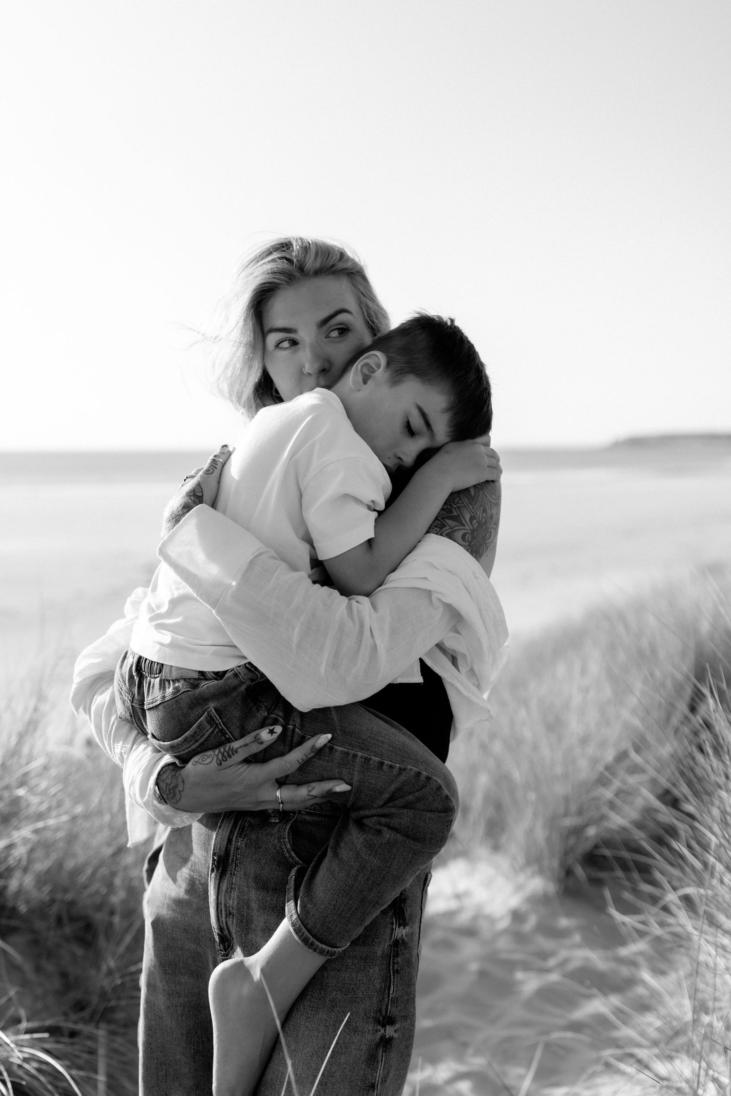 Black and white photos of a couple embracing in a windswept field.