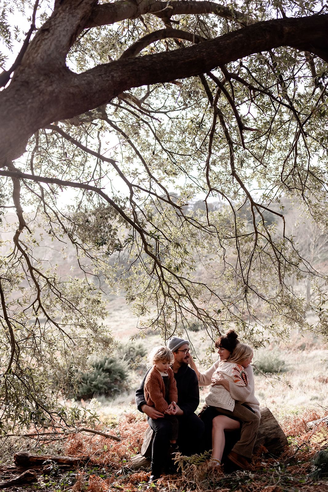 Family sharing joyful moments together under a large tree branch.