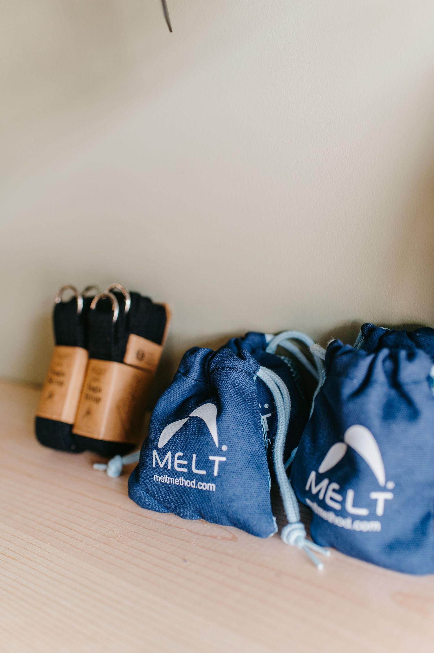 Blue MELT branded drawstring bags and workout equipment arranged on a light colored surface.