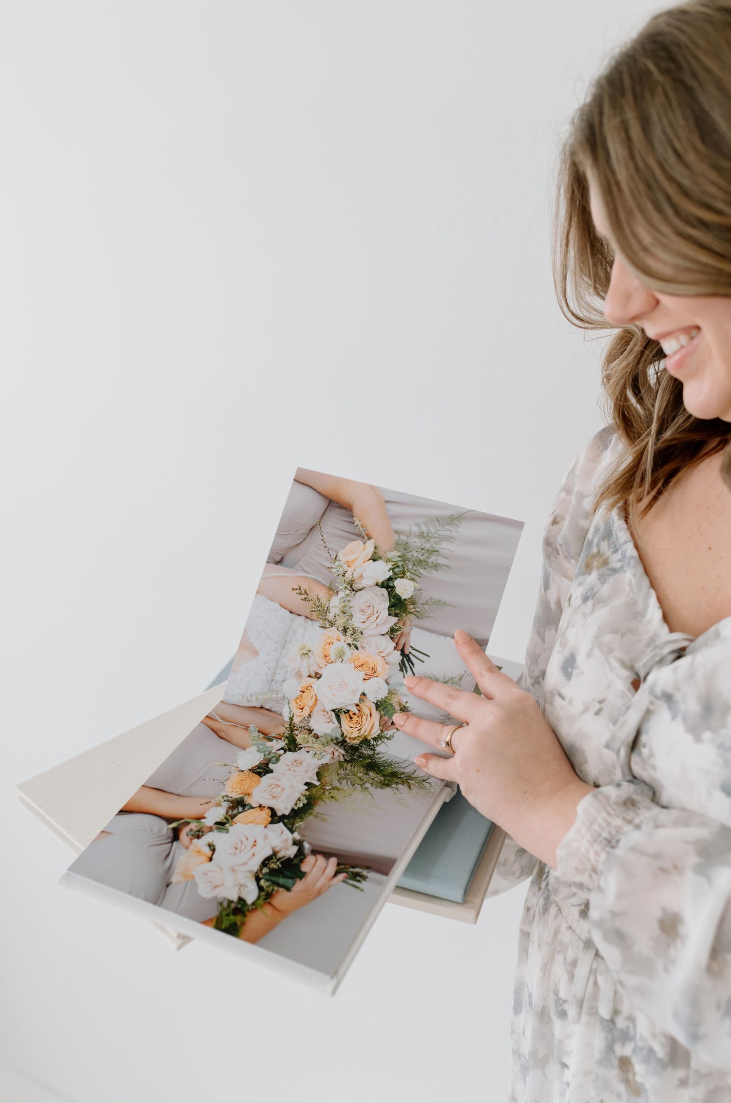 Someone in a floral print dress looks through wedding photos featuring delicate flower arrangements and decorations.