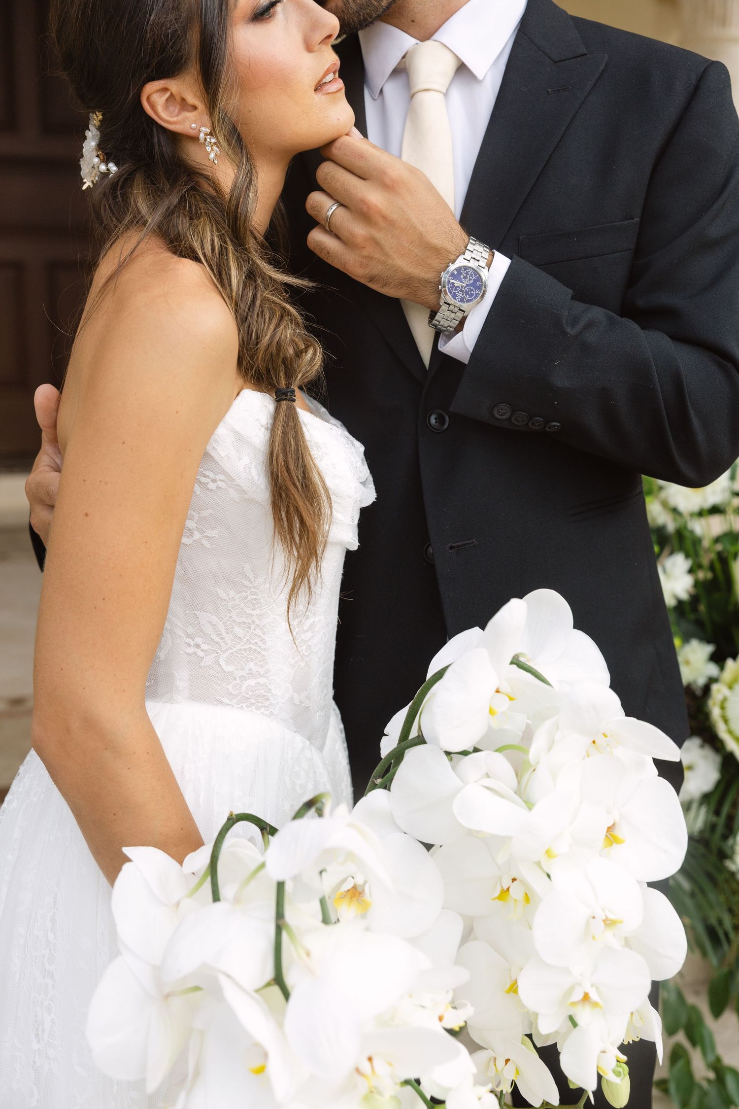 A romantic wedding moment captured with a beautiful white orchid bouquet in the foreground.