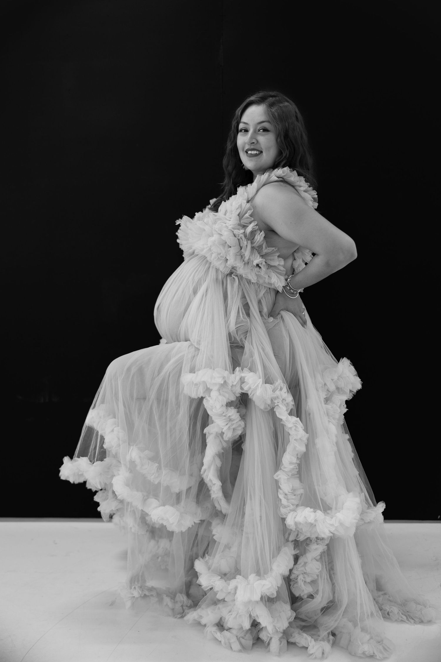 A dancer in a flowing white dress moves gracefully against a dark background in a striking performance sequence.