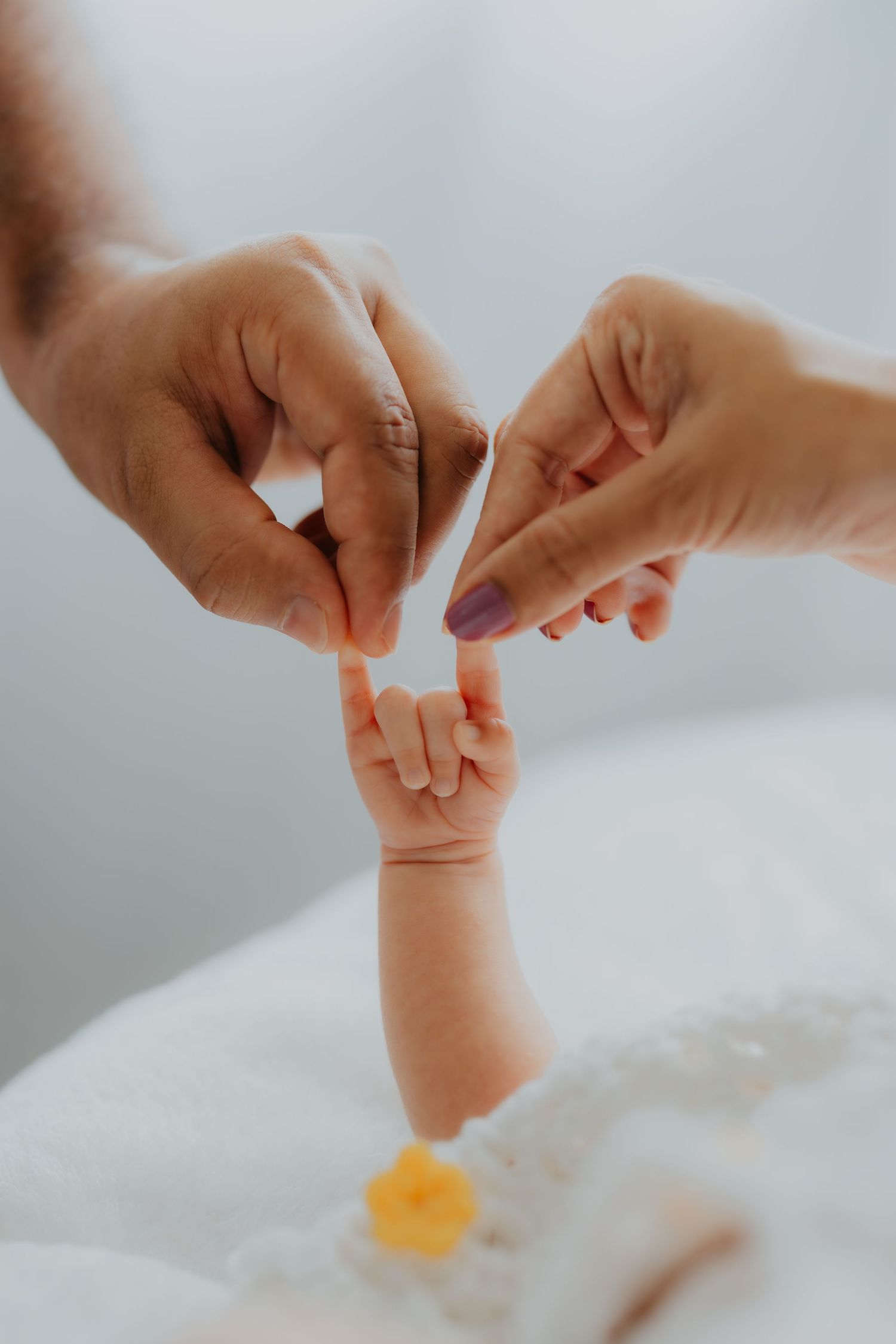 Two parents gently holding their newborns tiny hand together in a tender moment.