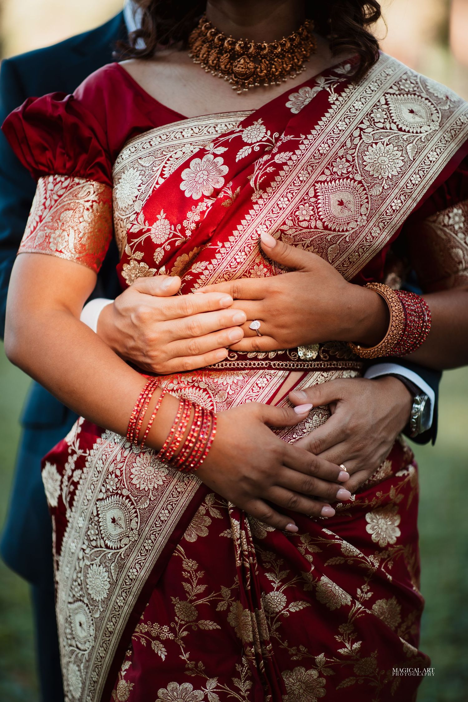 Close-up of bride in red and gold embroidered saree with mehndi hands and gold jewelry.