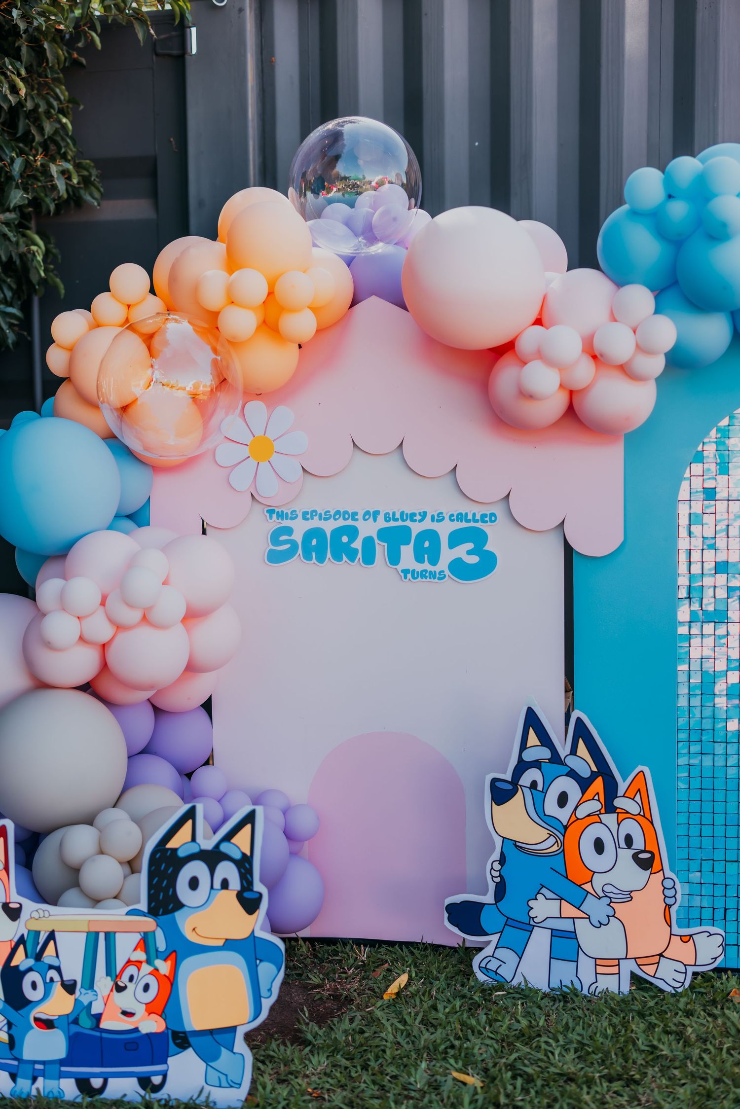 Bluey themed birthday party backdrop with balloon arch and character cutouts for Sarita.