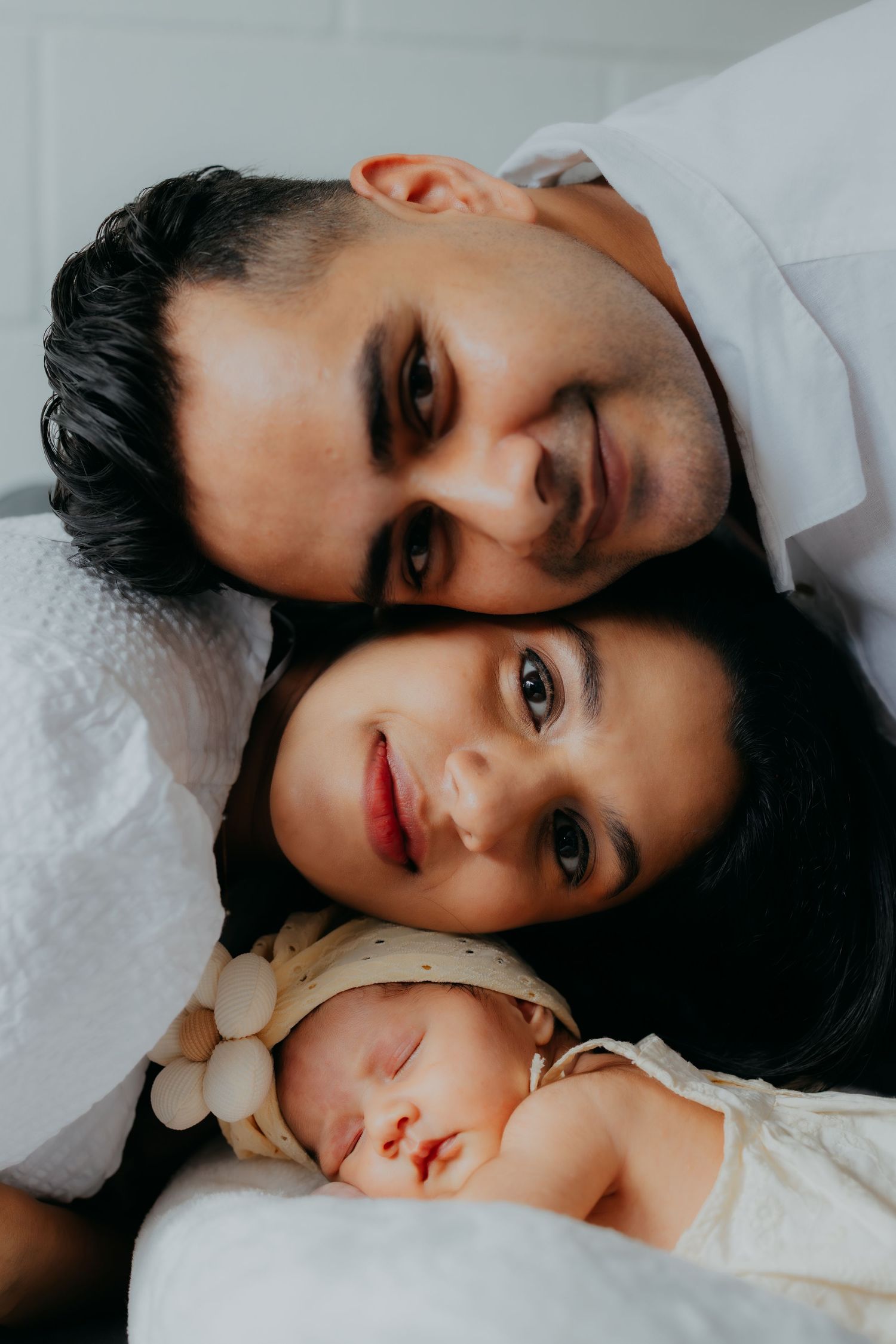 Loving new parents lying close together with their peaceful sleeping newborn baby.