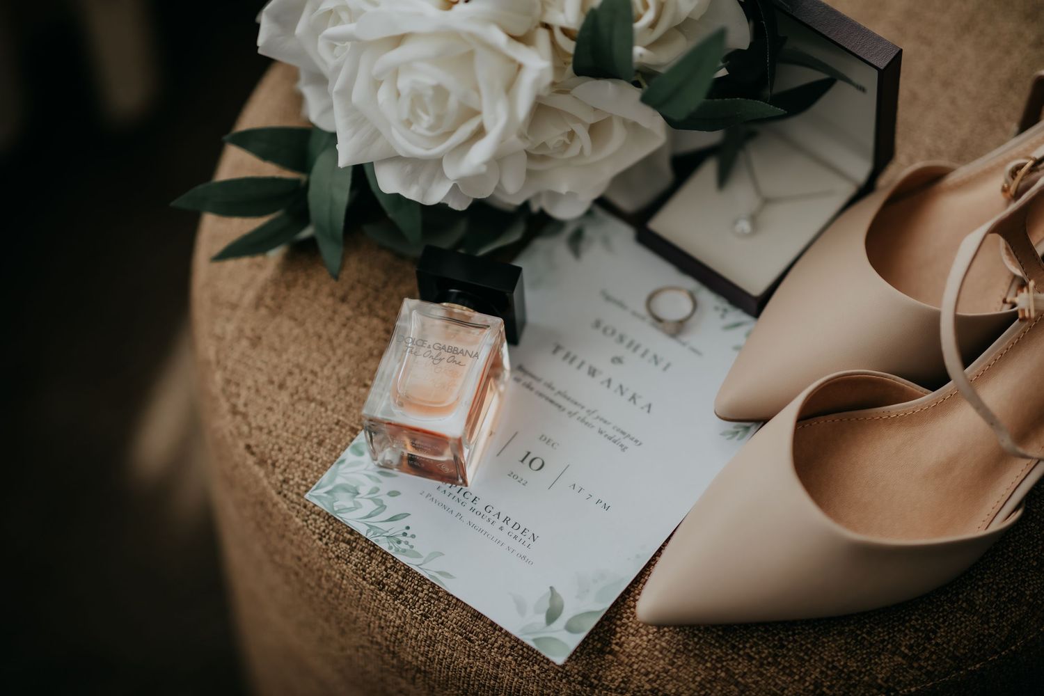 Elegant wedding flat lay with nude heels, perfume, invitation, and white rose bouquet.