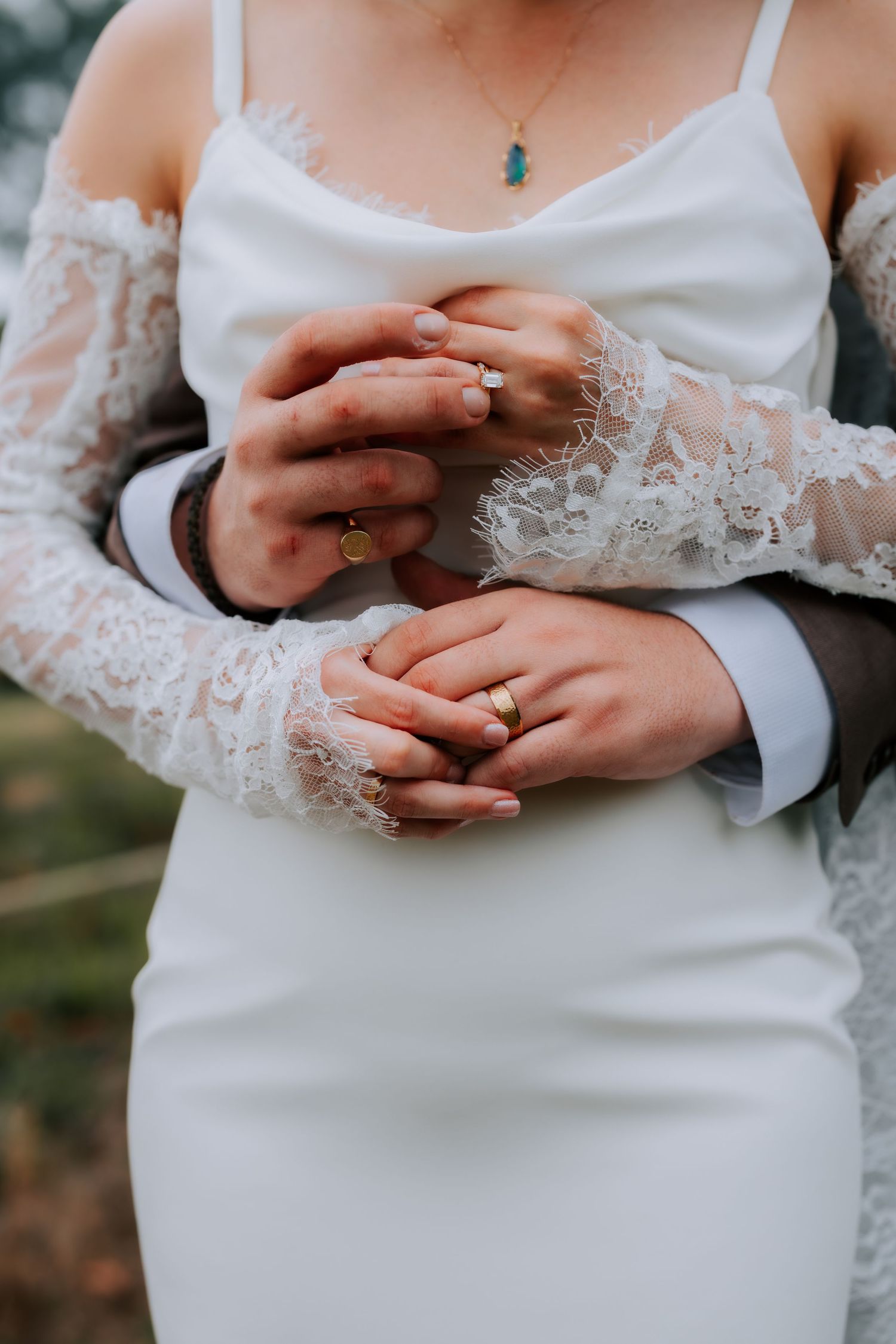 Close-up of bride and groom holding hands showing gold wedding rings after ceremony.
