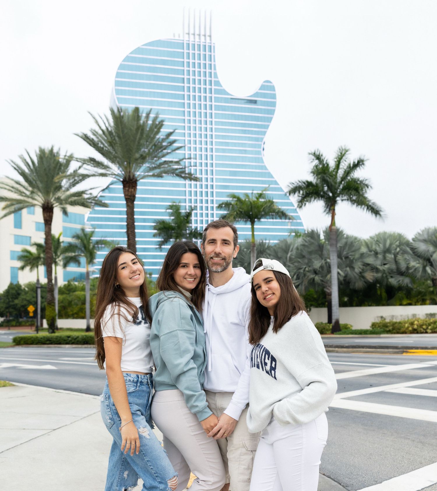Friends enjoying a casual photoshoot together on a palm-lined street with modern buildings in the background.