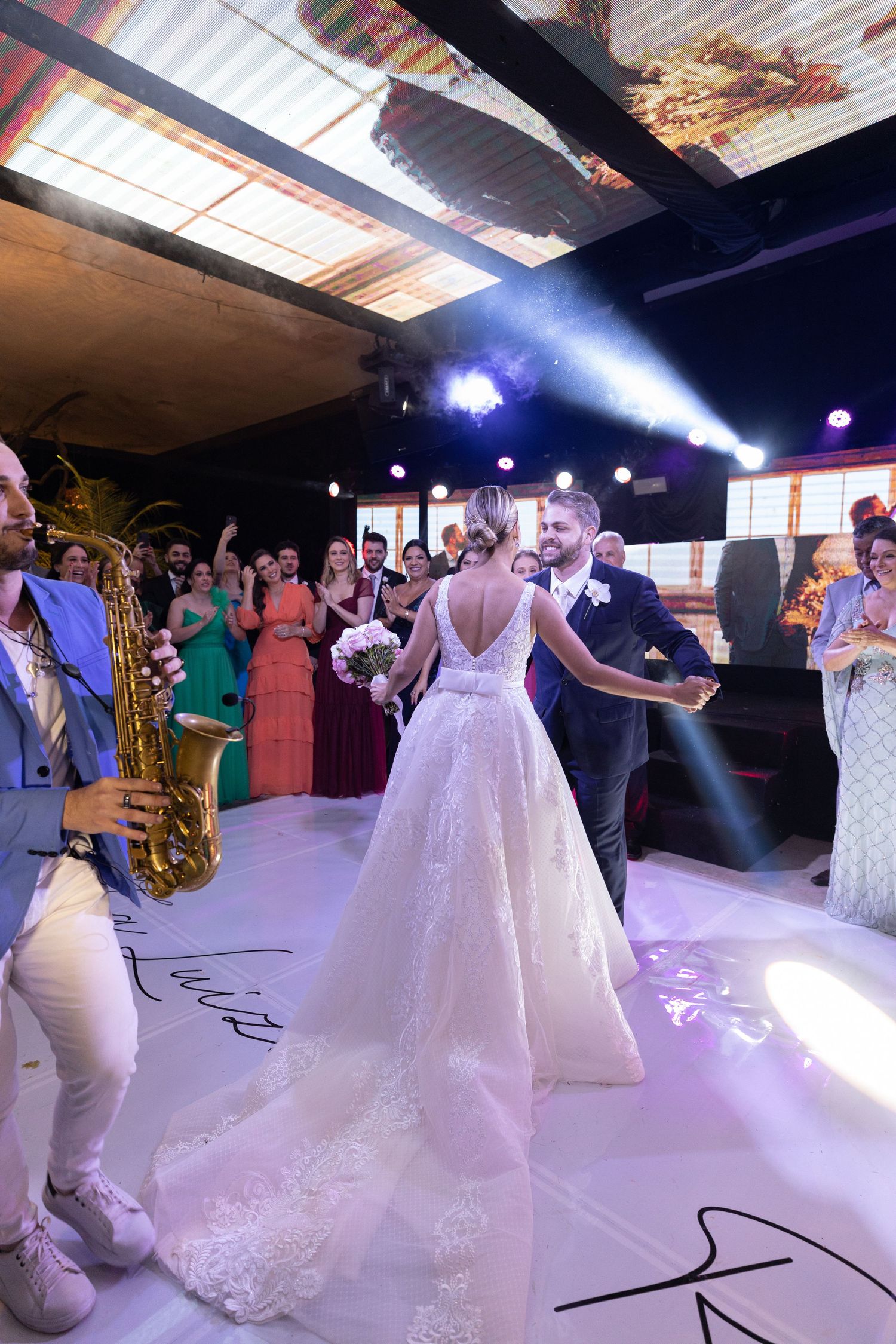 Wedding reception dance floor with white dress and party lights.