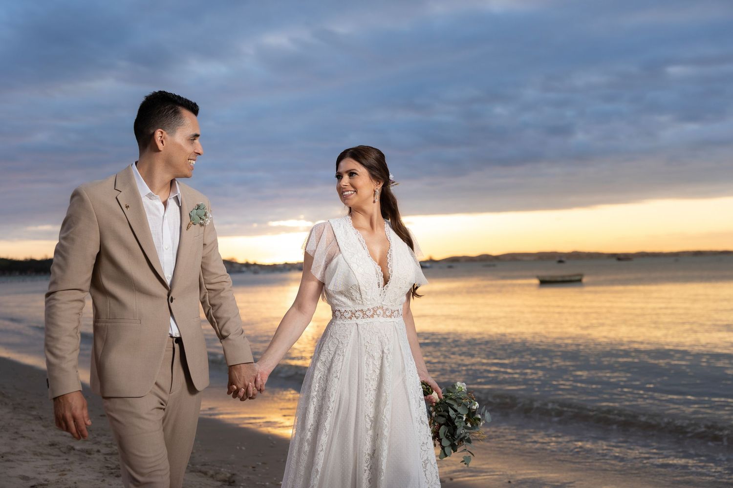 A romantic beach wedding photoshoot at sunset with the couple walking along the shoreline.