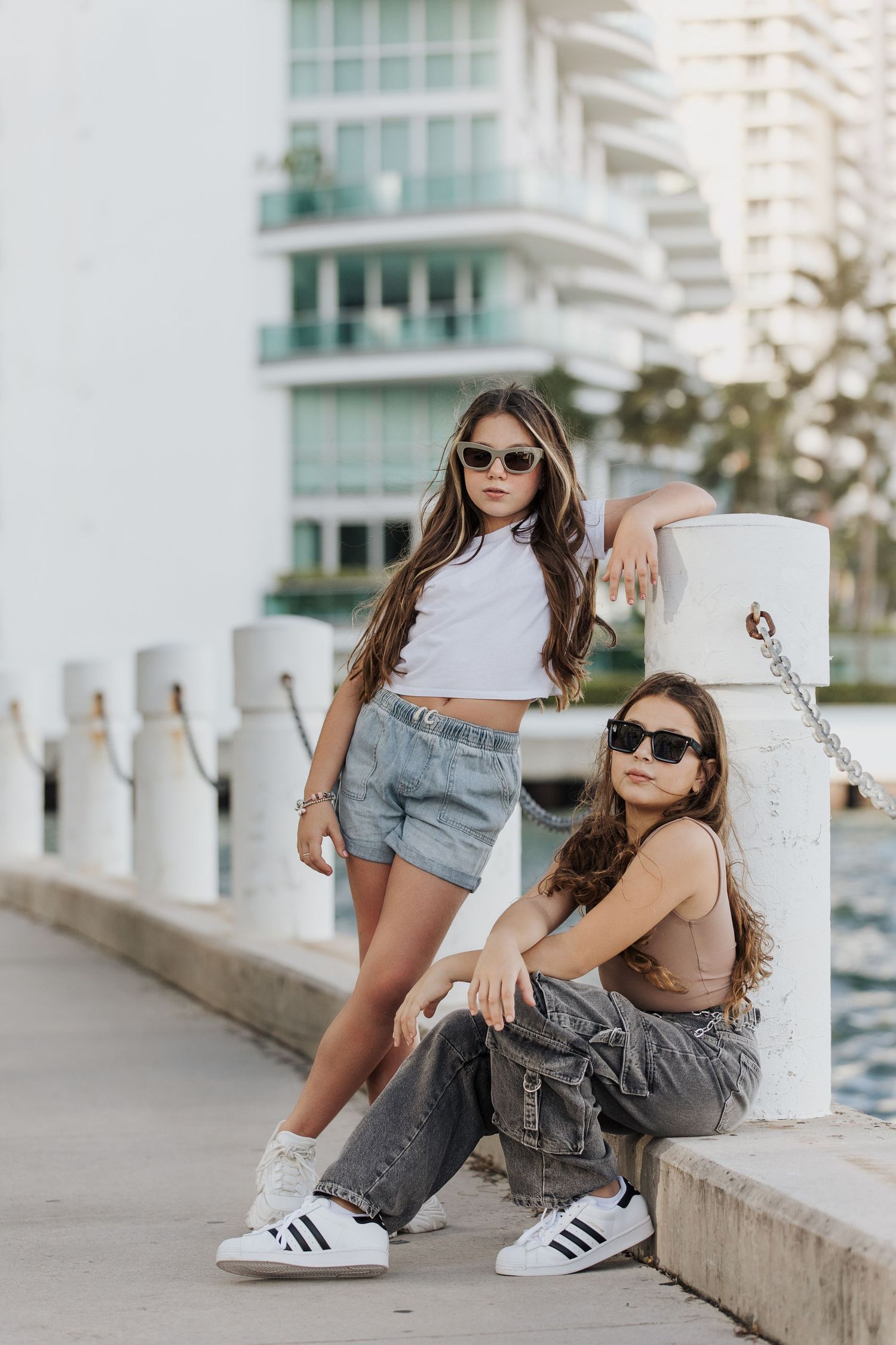 Casual urban photoshoot featuring trendy outfits and modern architecture in the background.