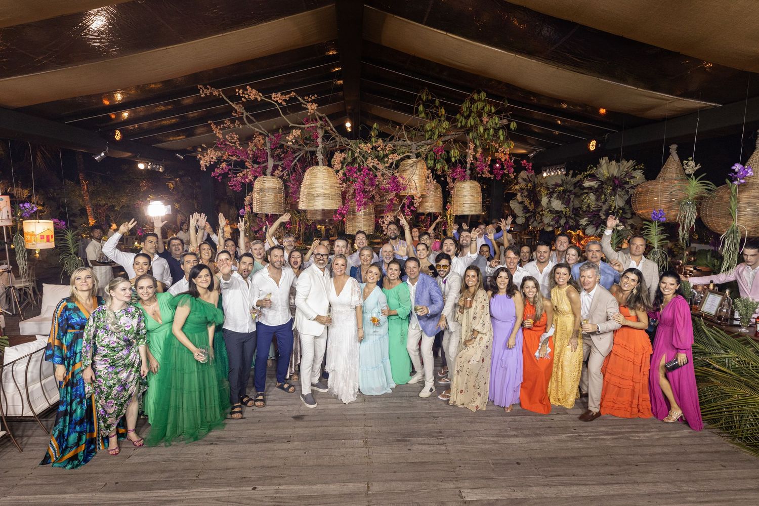 Large group wedding photo with guests wearing colorful formal attire.