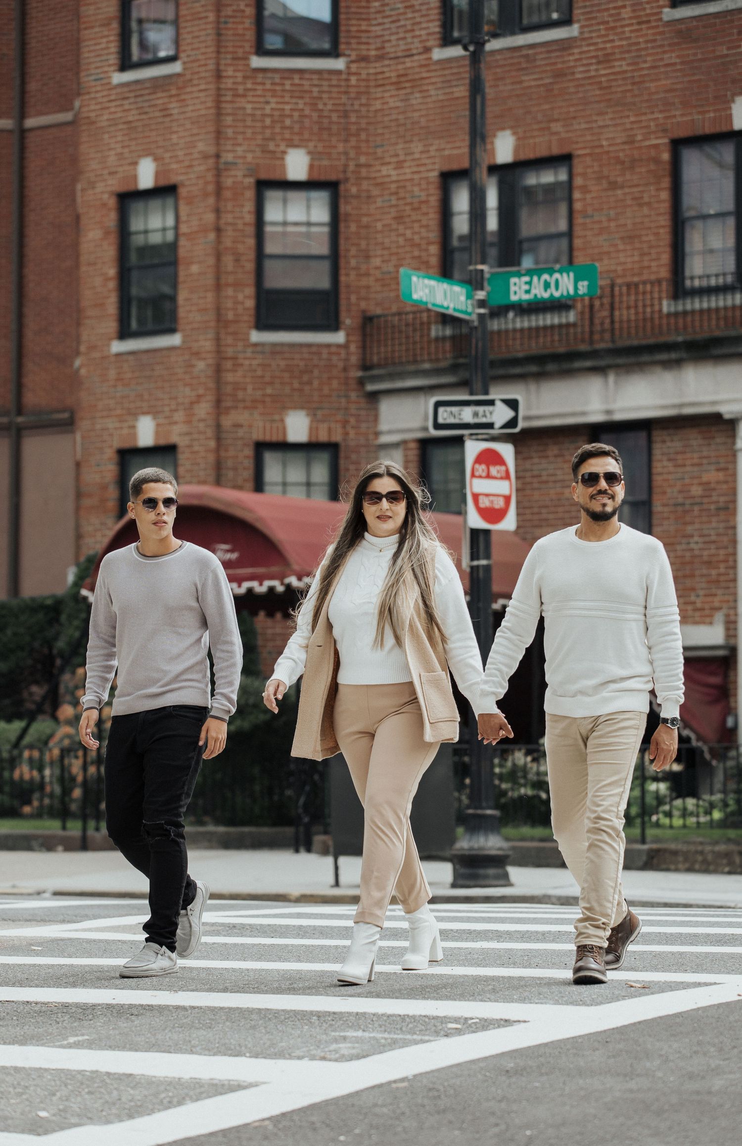 Stylish group walking across an urban crosswalk wearing coordinated neutral outfits.