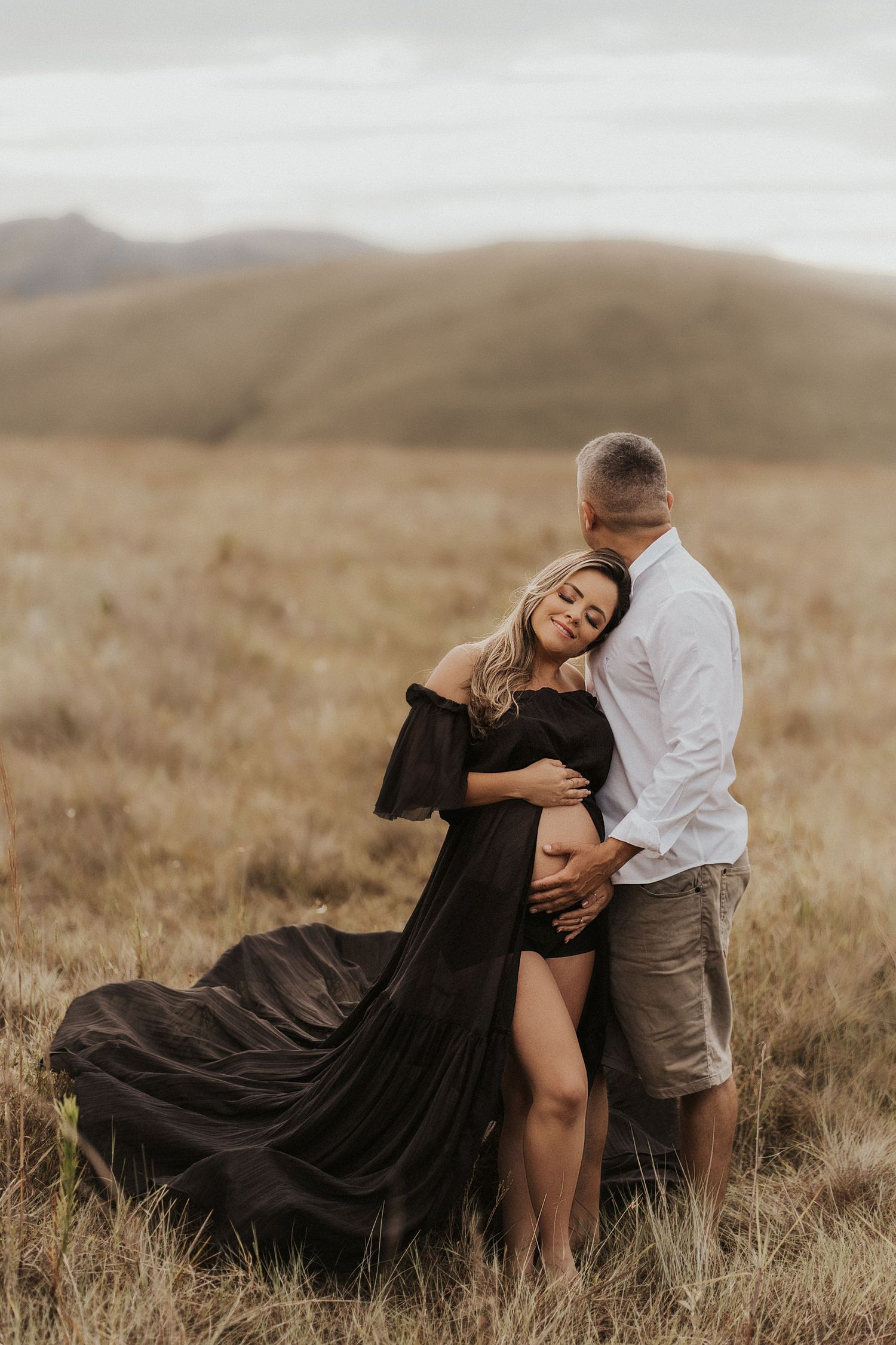 Romantic countryside photoshoot in a golden field with flowing black dress.