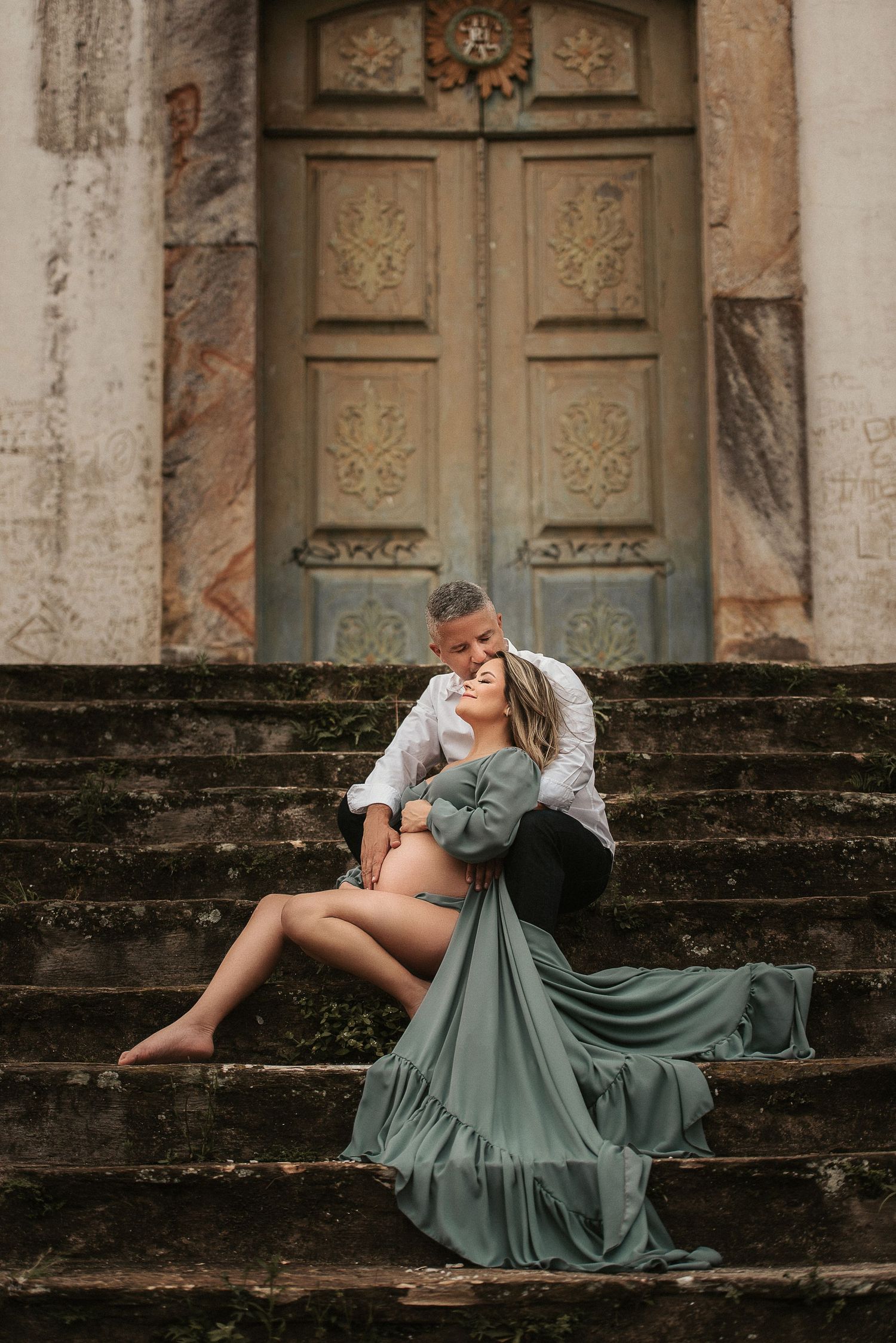 Intimate couple photoshoot on vintage stone steps with flowing sage green dress.