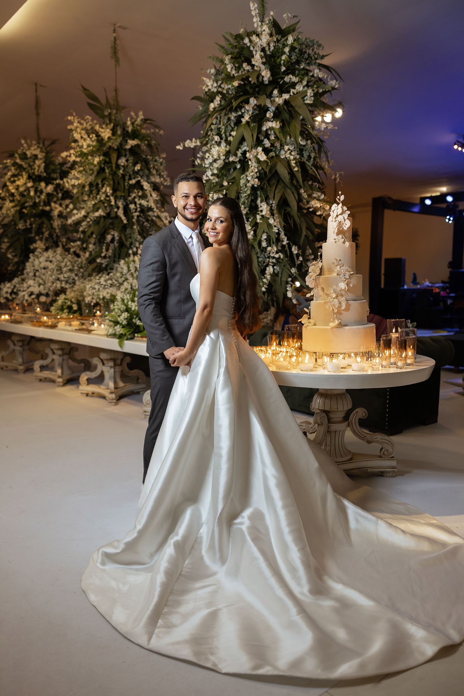 A wedding couple shares an intimate moment on their special day surrounded by elegant floral arrangements and candlelight.