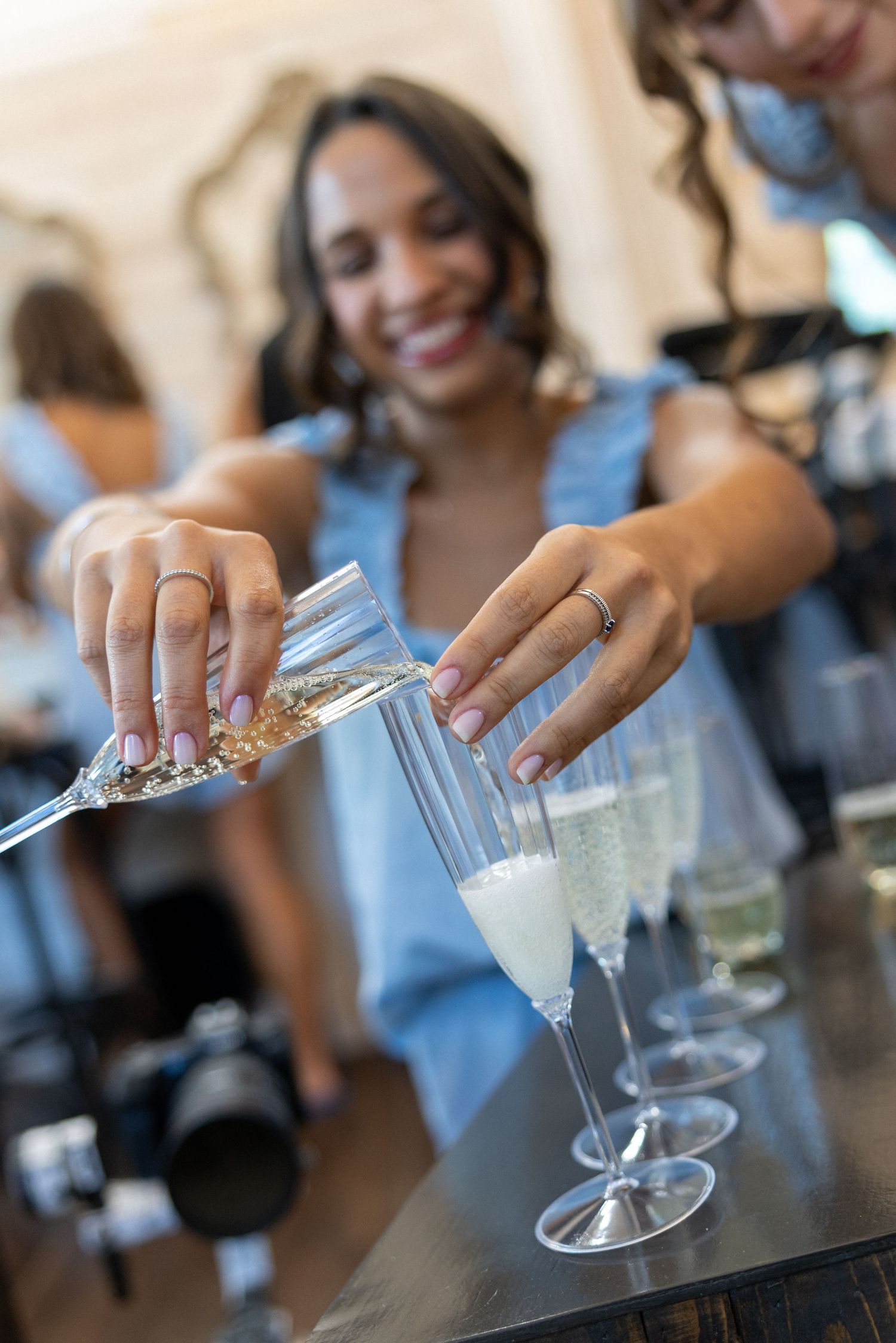A bridesmaid pours champagne into an elegant flute glass at a making of the bride morning session