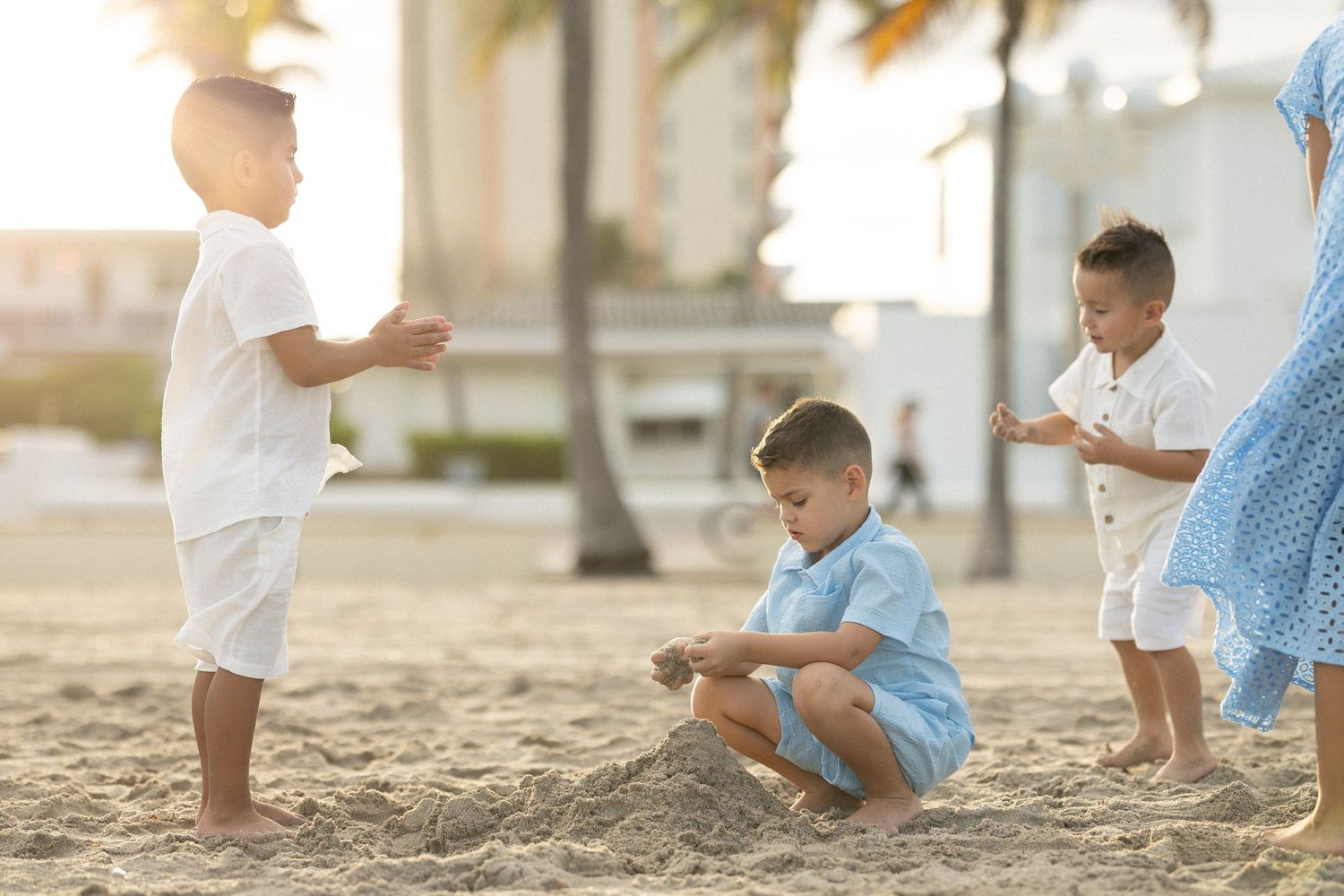 Children playing and running on a sandy beach during golden hour with soft sunlight filtering through.