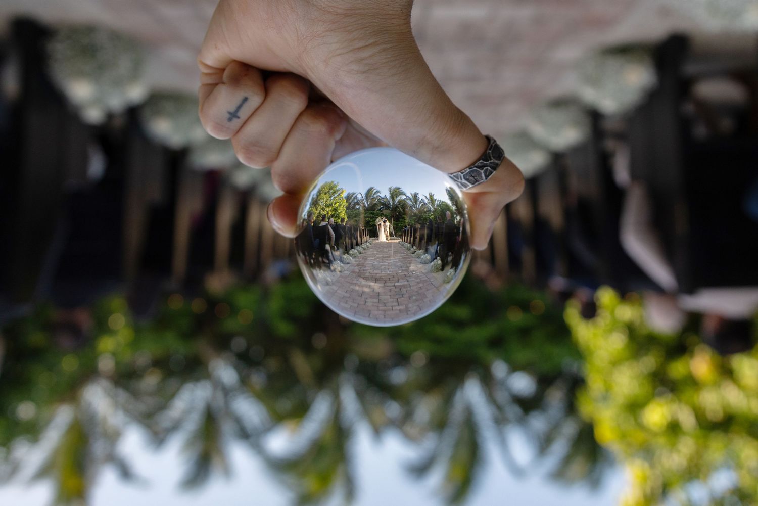 A glass sphere reflects an upside-down view of a garden landscape with trees and greenery in sunlight.
