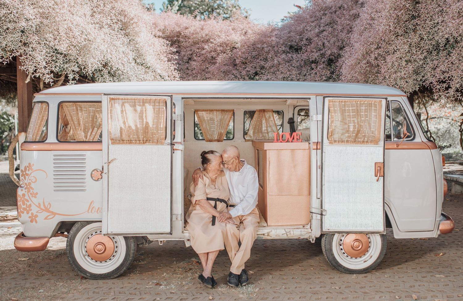 Vintage VW van parked under blooming cherry blossom trees in spring.