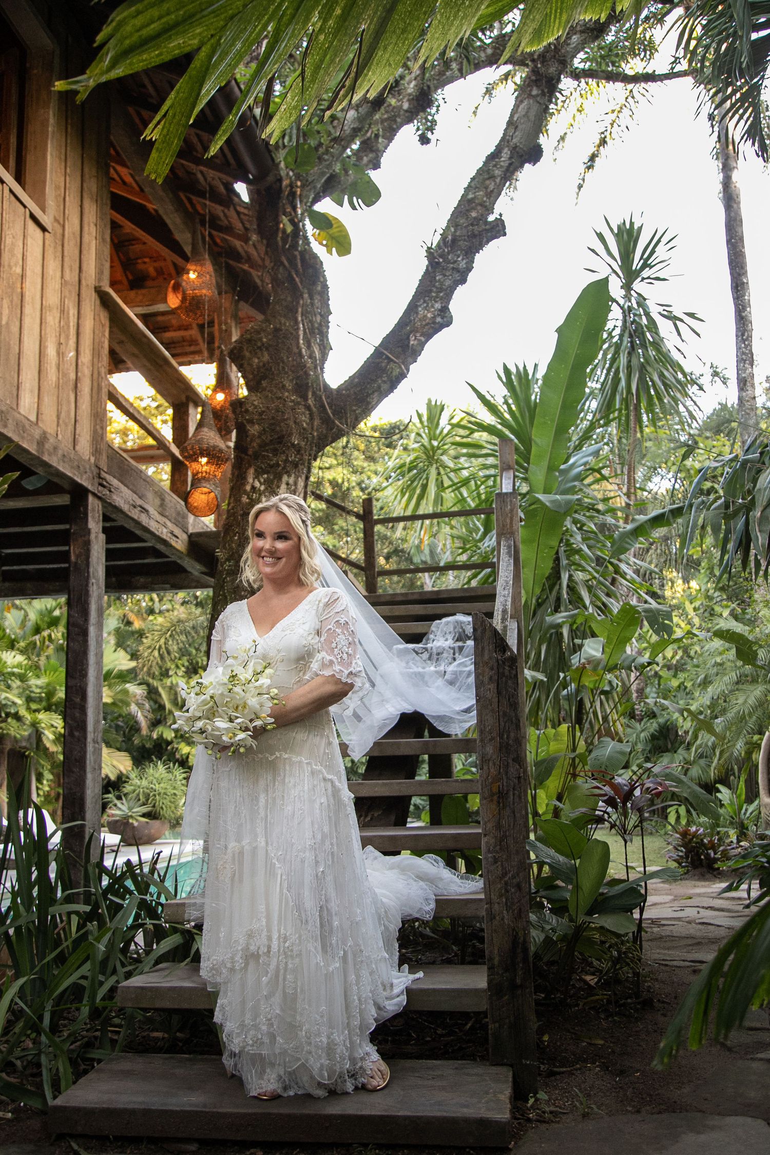 A bridal portrait session on a rustic wooden deck surrounded by tropical plants.