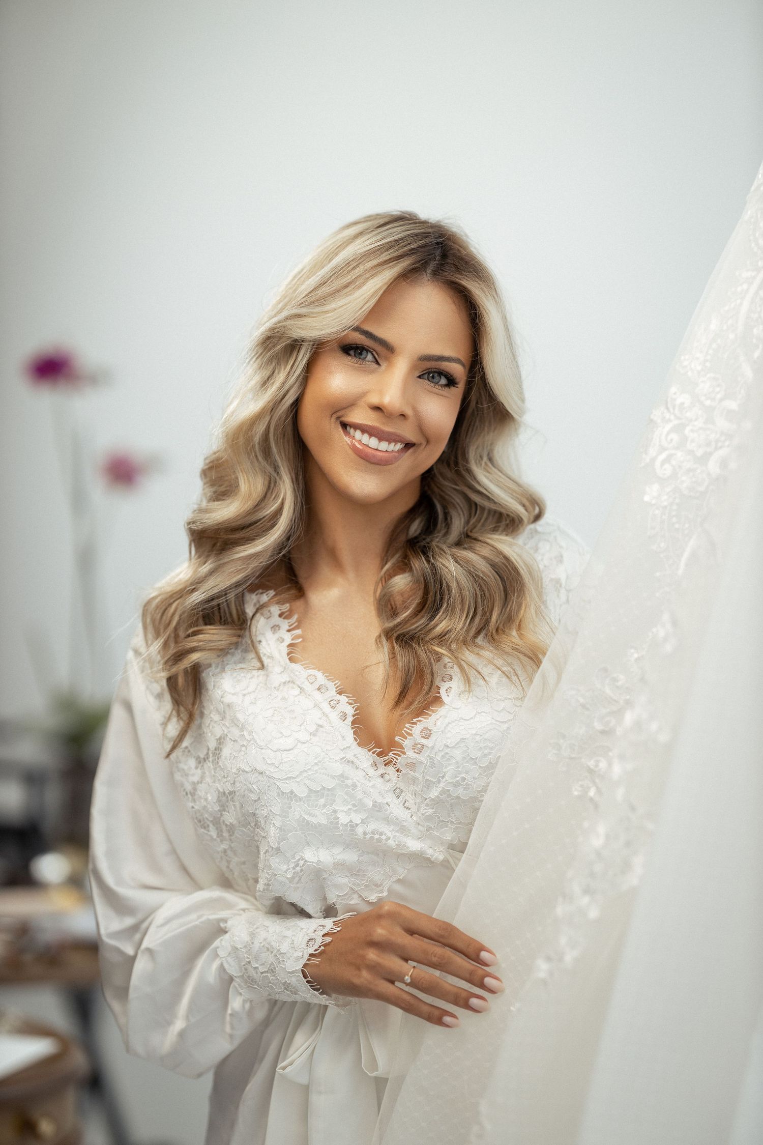 Soft white lace robe with delicate details photographed in a bright room.