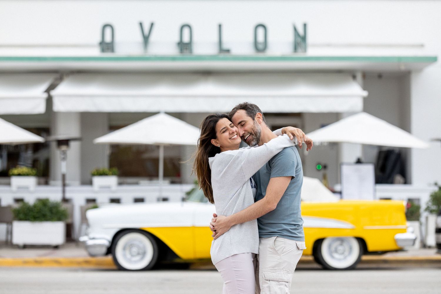 Romantic moment captured at a vintage car venue with classic automobiles in the background.