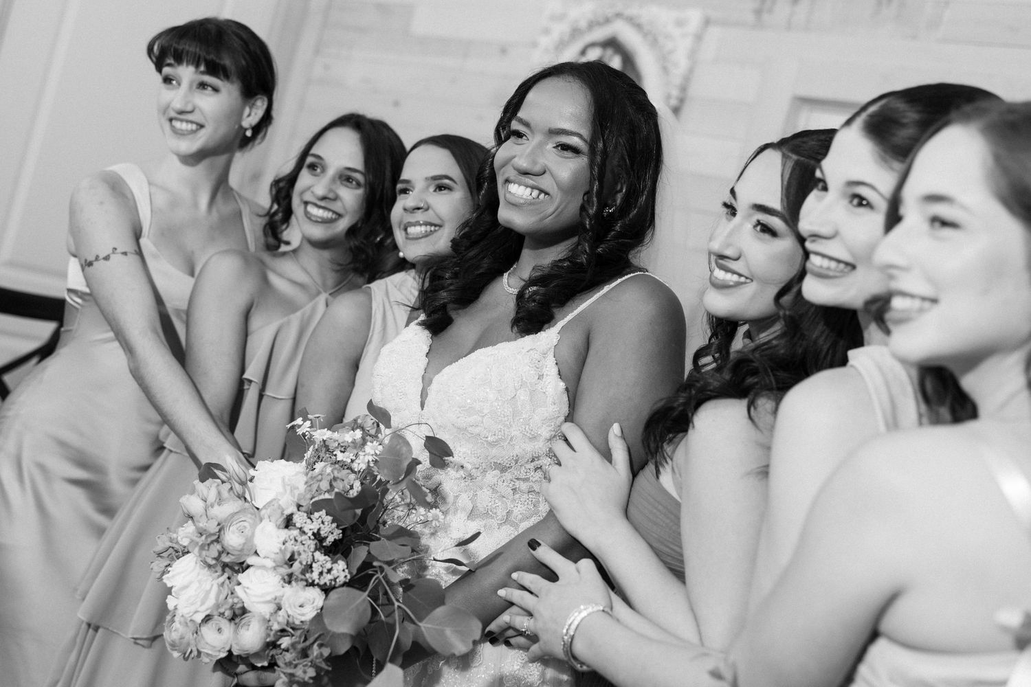 A joyful group of people in formal attire laugh and embrace while celebrating at an elegant event.