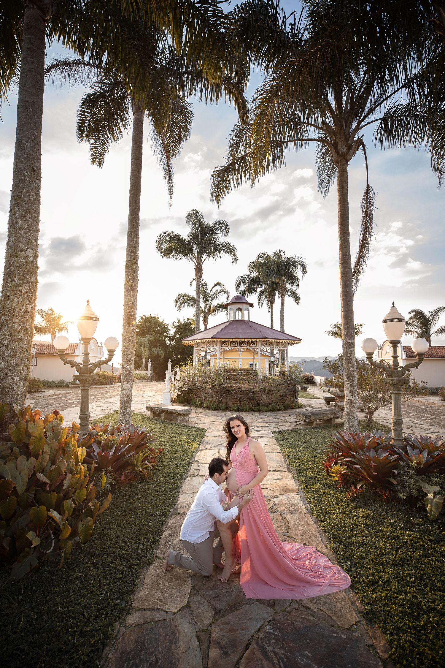 Romantic photoshoot in a tropical garden with palm trees and gazebo at sunset.