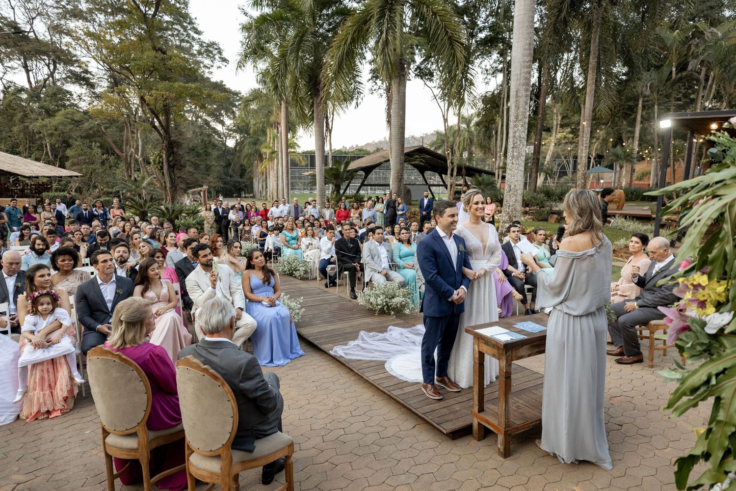 Outdoor wedding ceremony setup with palm trees and wooden benches.