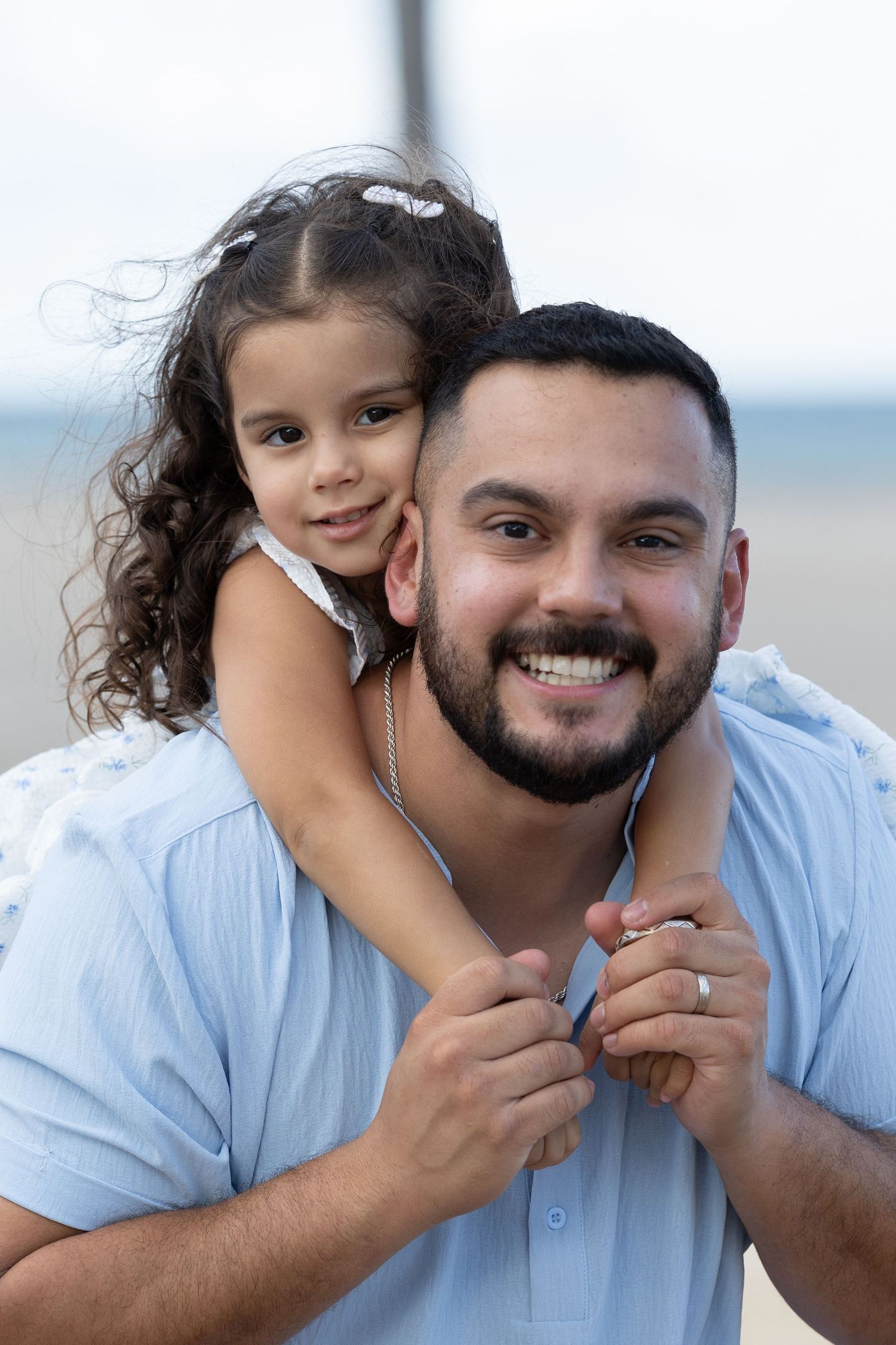 A series of candid moments showing a parent and child playing together at the beach in matching light blue outfits.