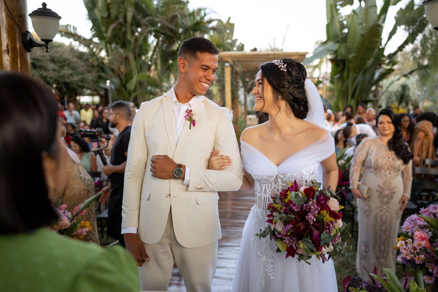 Wedding celebration with purple floral arrangements in an outdoor garden setting.