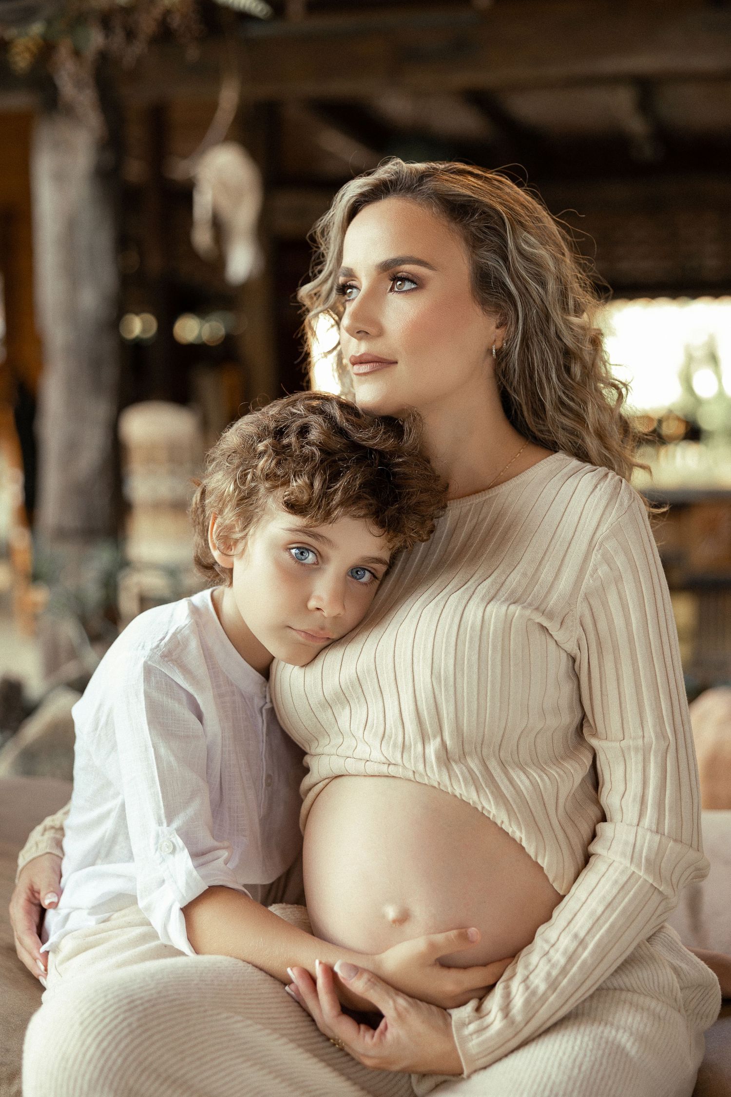 Maternity photoshoot in cream sweater with intimate poses in rustic setting.