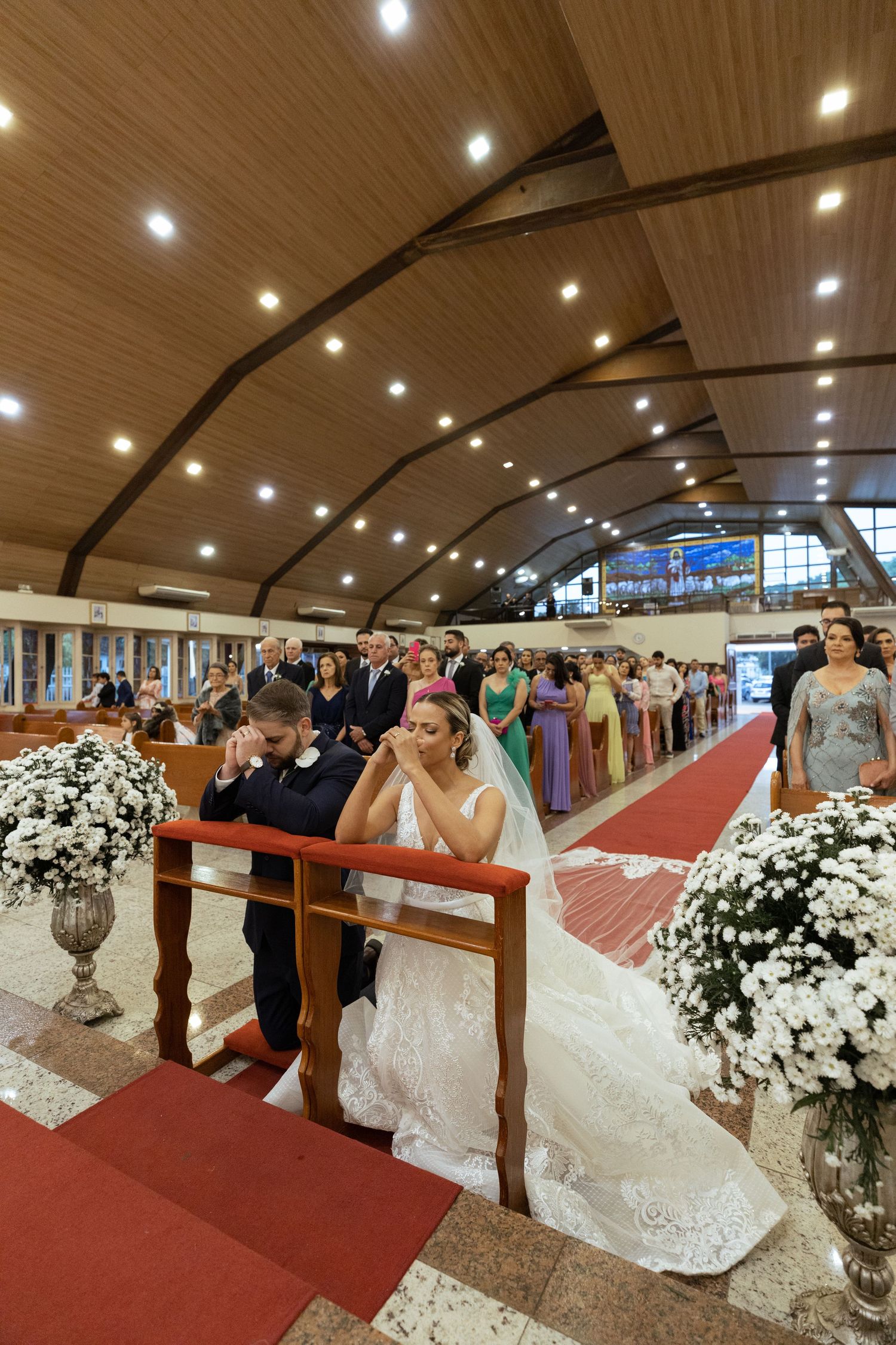 Church wedding ceremony with white floral decorations and wooden pews.