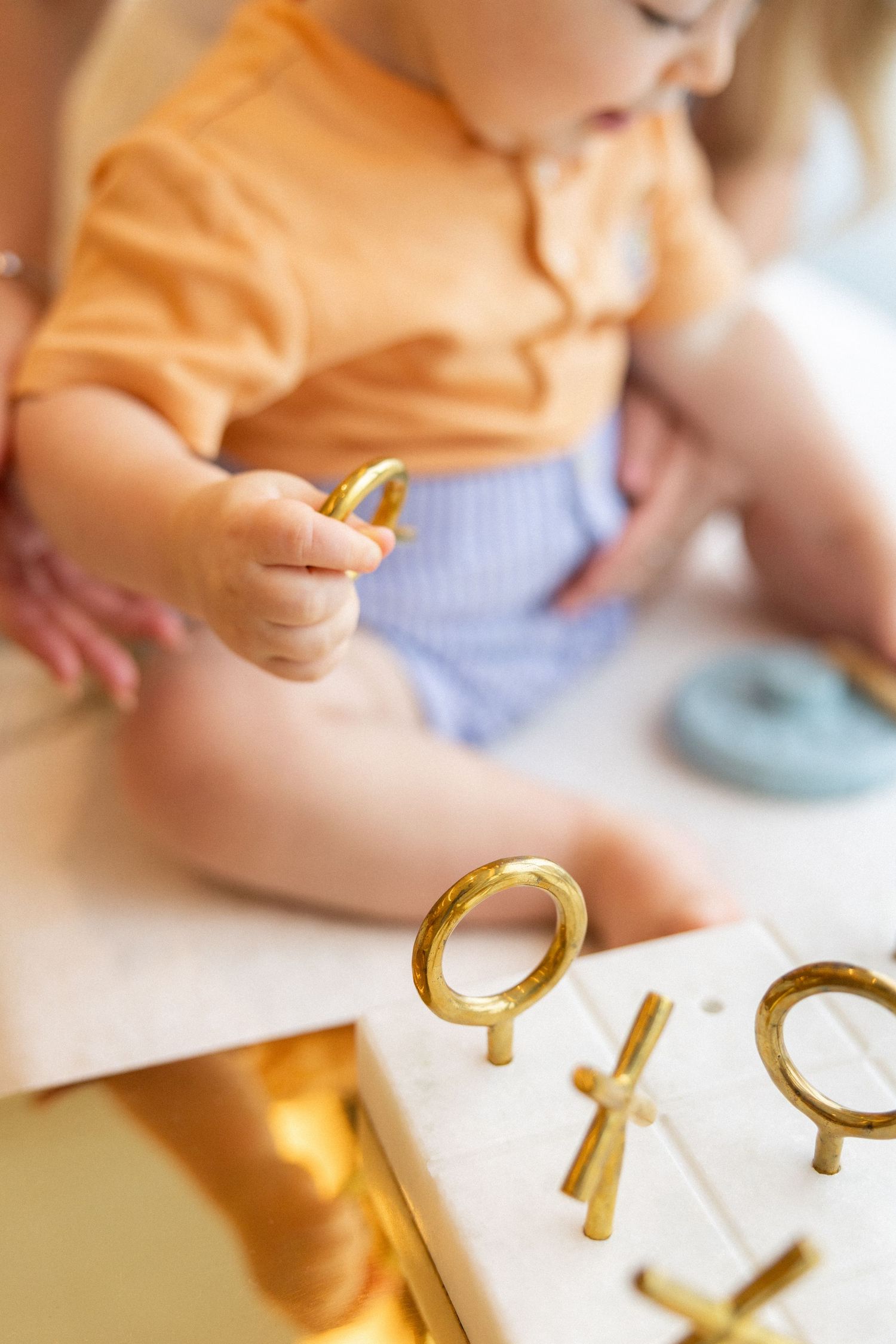 Child's hands playing with gold number-shaped learning toys on a white surface.