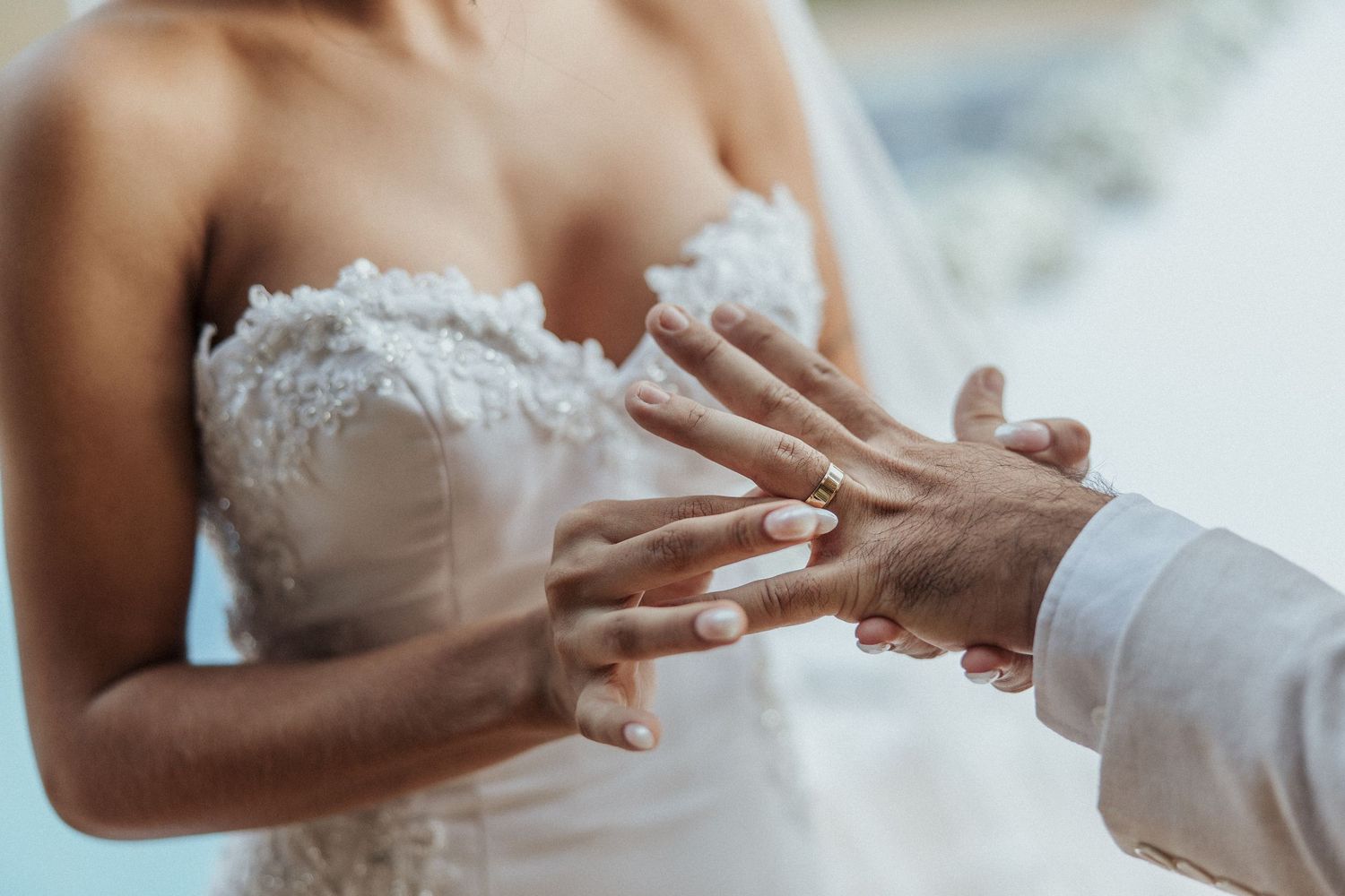 Close-up shots of hands holding rings during a wedding ceremony.