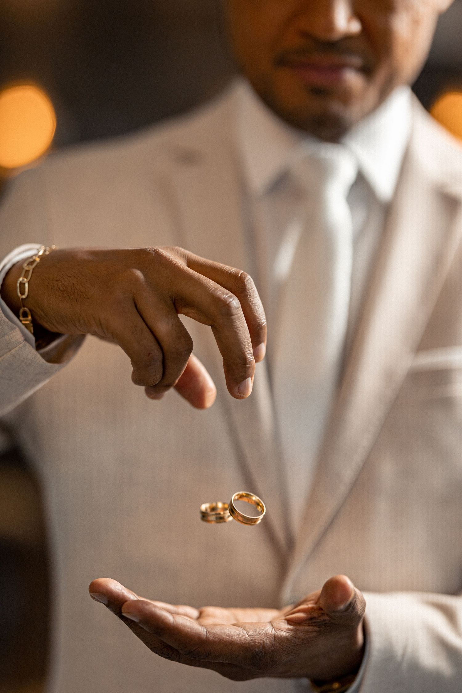 Wedding rings suspended between groom’s hands during detail shot in Florida wedding