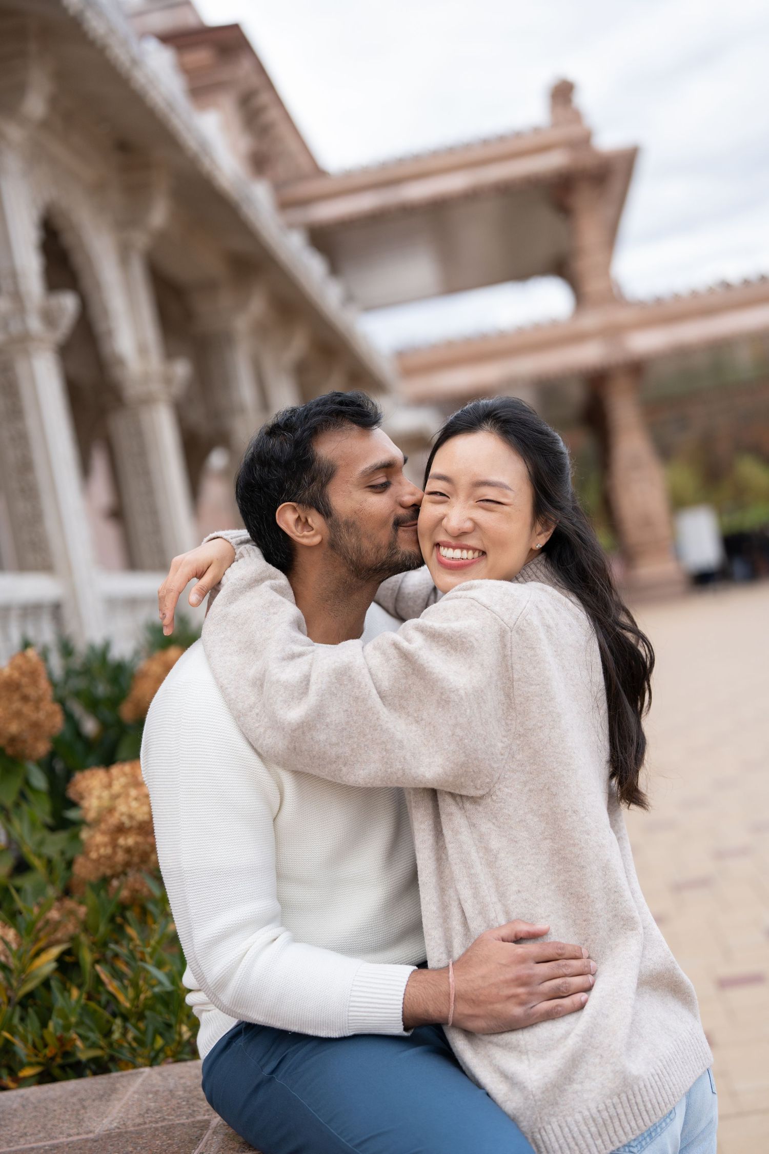 A couple shares tender moments together while sitting on stone steps at a historic building.