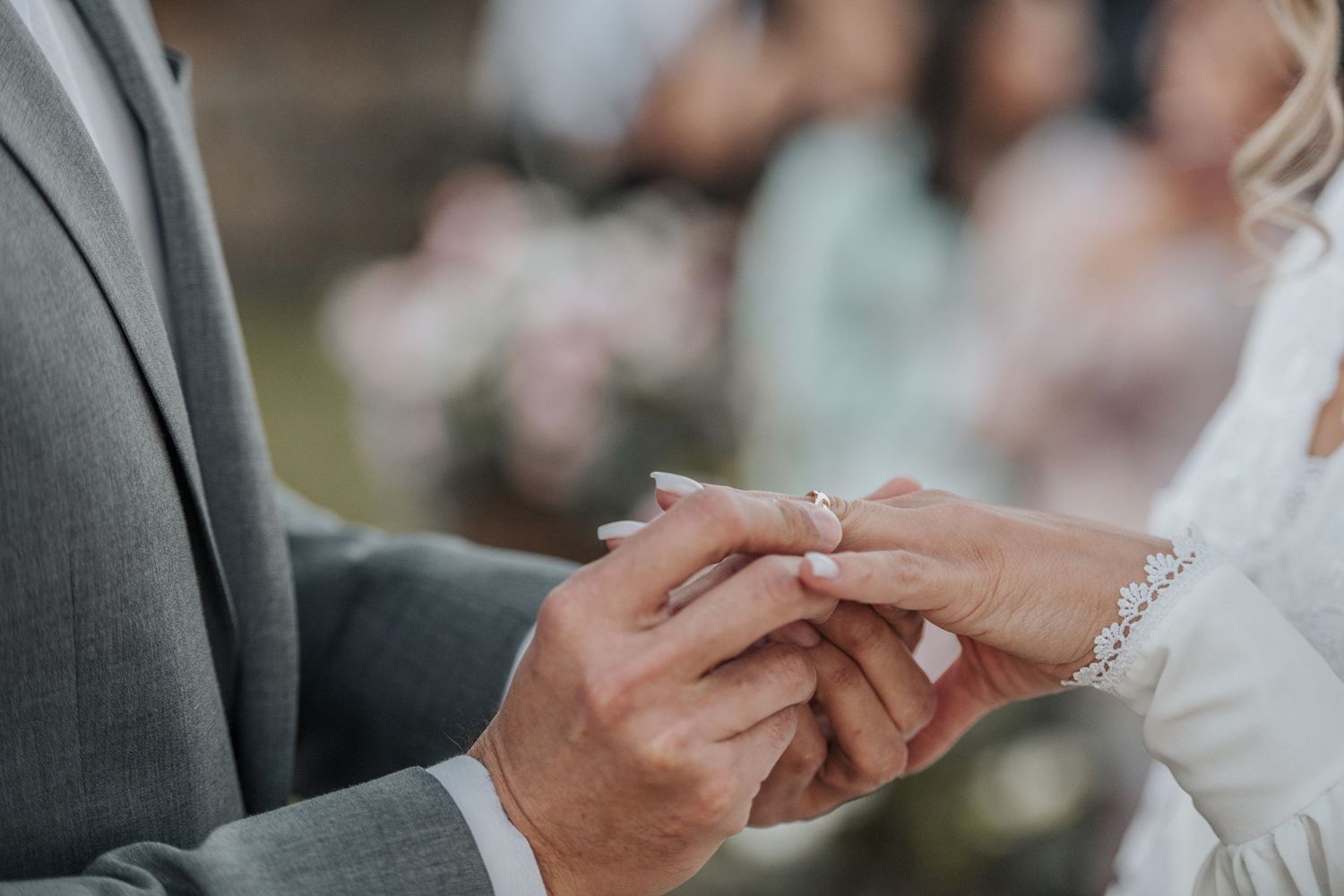 Close-up of hands exchanging rings during wedding ceremony.