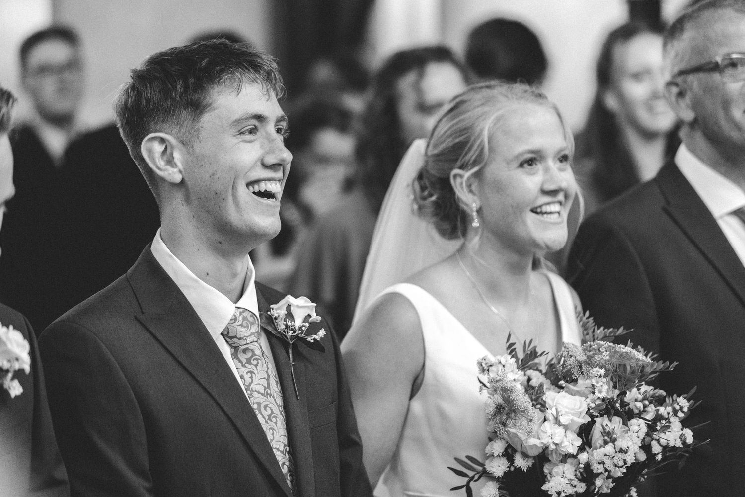 Joyful black and white portrait of newlyweds during wedding ceremony.