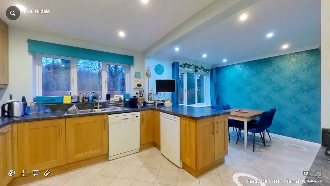 Spacious kitchen with wooden cabinets and turquoise accent wall featuring modern appliances and dining area.