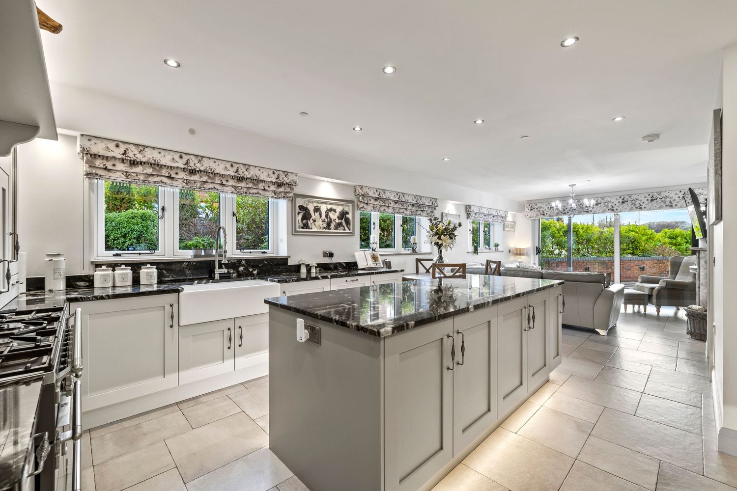 Luxurious open-plan kitchen with grey cabinets, black countertops, and abundant natural light.