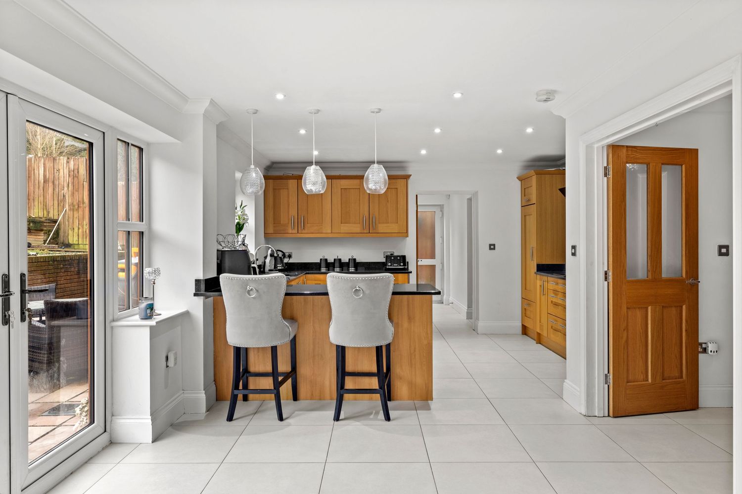 Modern kitchen interior with wooden cabinets, pendant lights and breakfast bar seating.